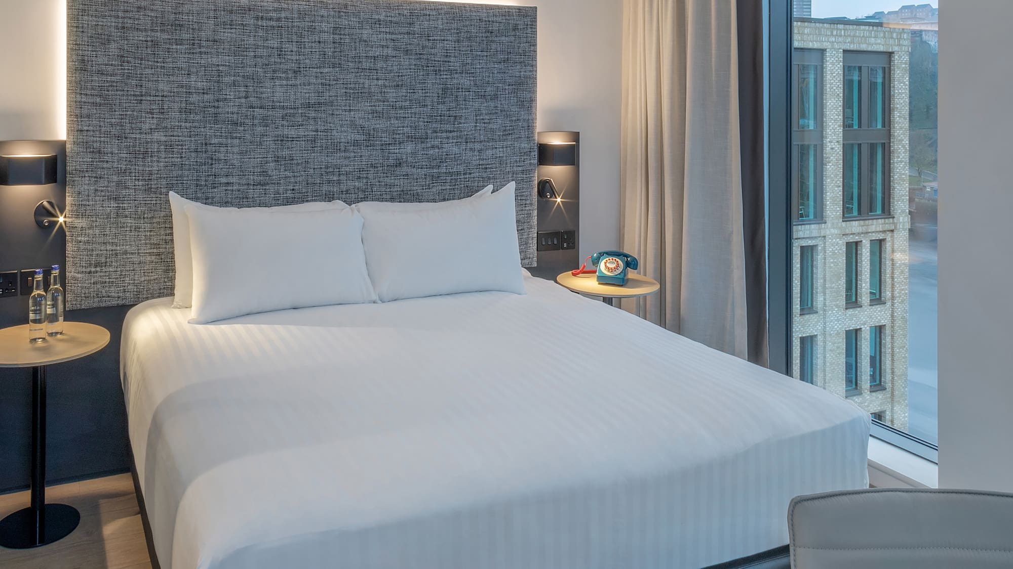 a bed with a headboard and a table with a telephone on it