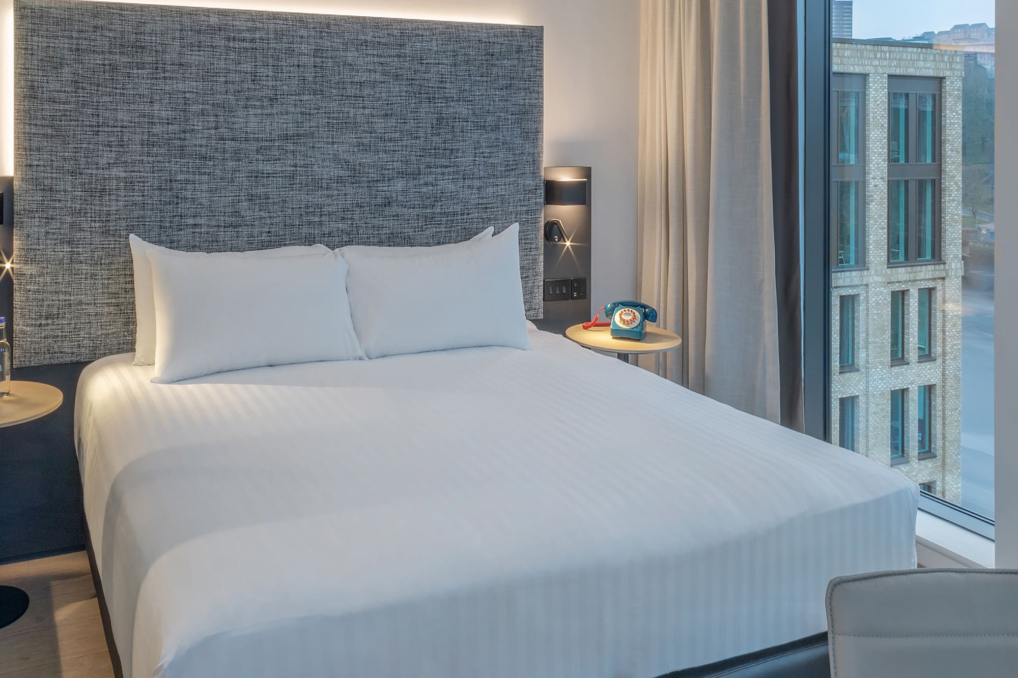 a bed with a headboard and a table with a telephone on it