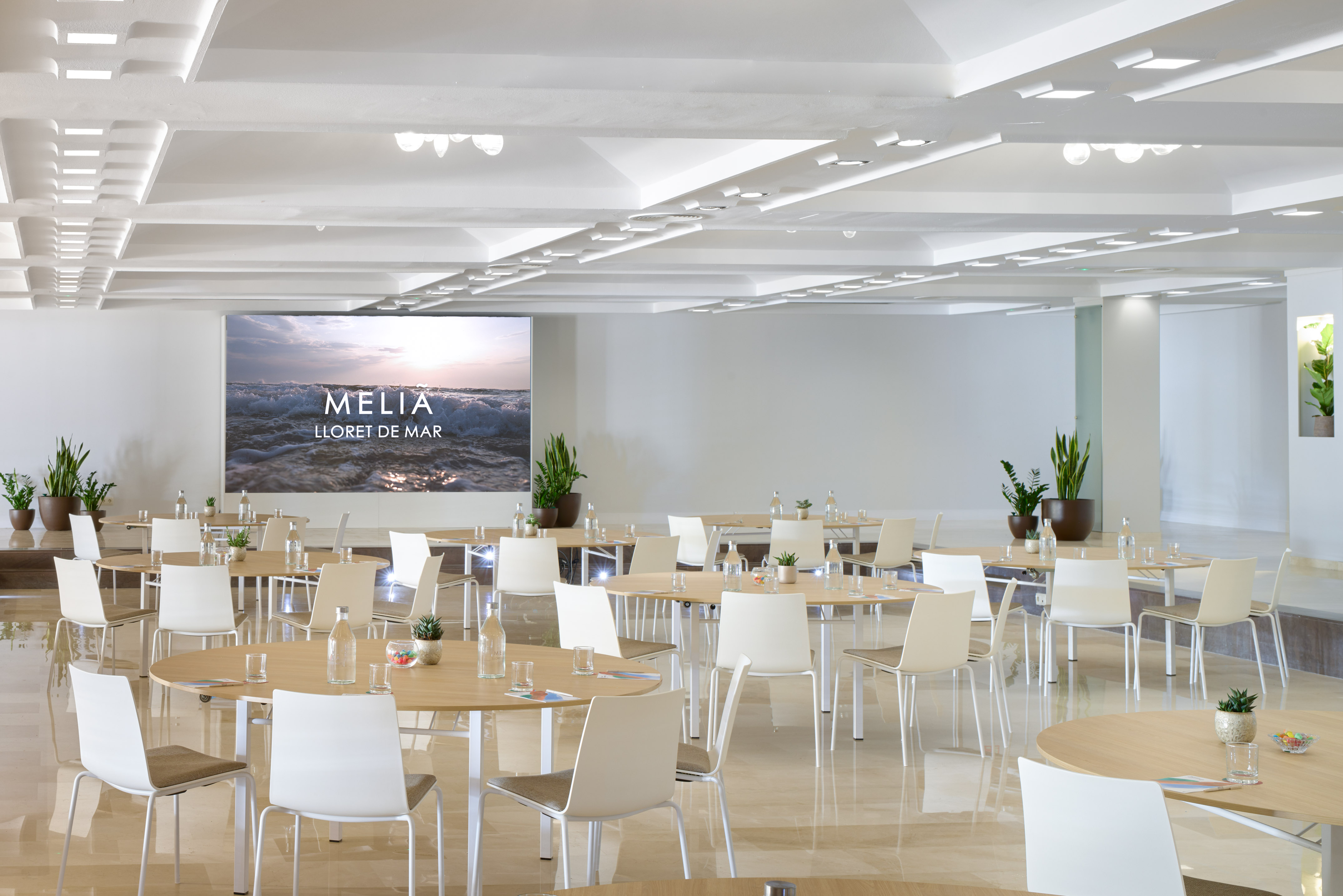 Modern Melia Lloret de Mar conference room with tables, chairs, and large screen.