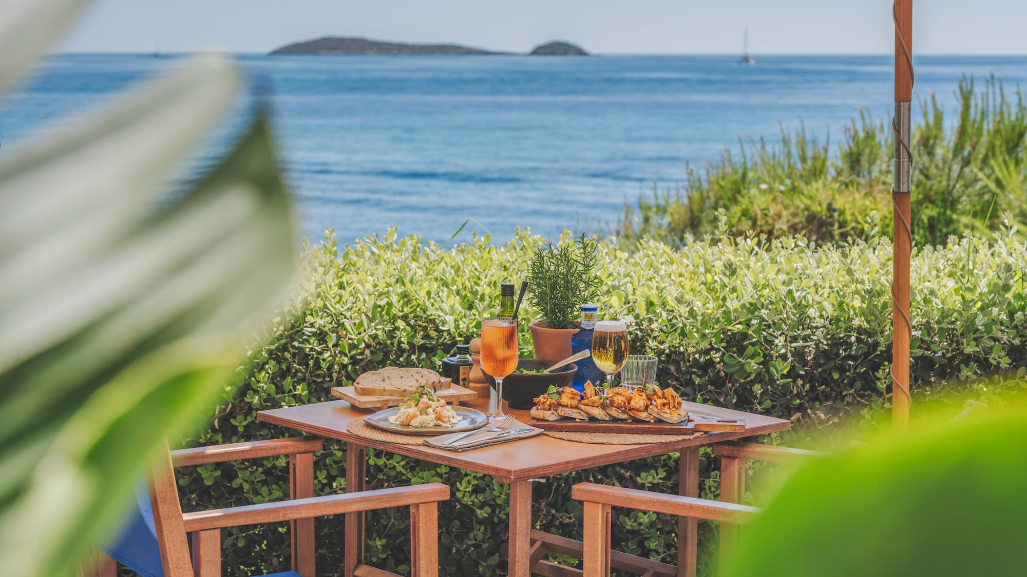 Mediterranean outdoor dining with tapas, drinks, and sea view.