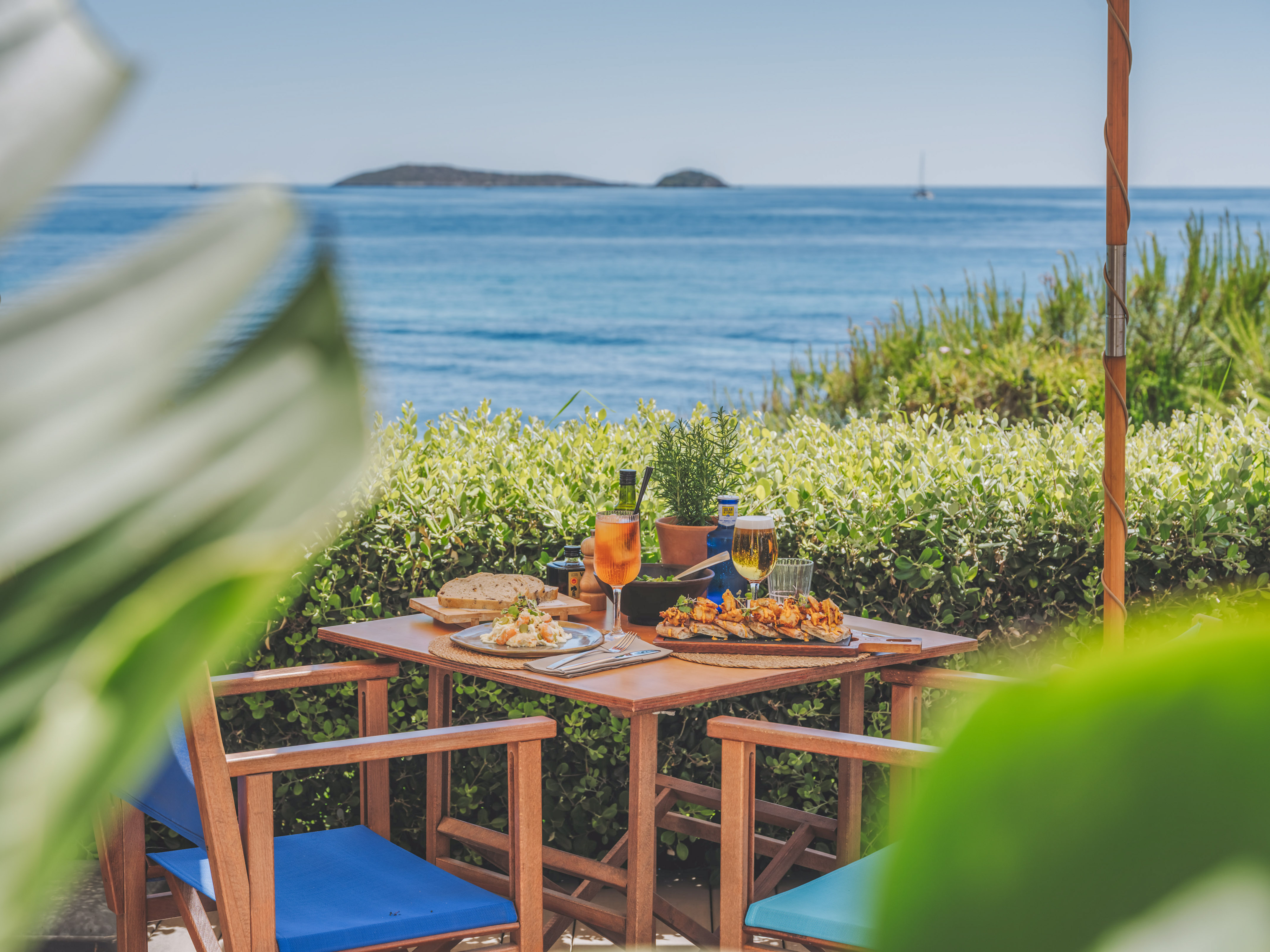 Mediterranean outdoor dining with tapas, drinks, and sea view.