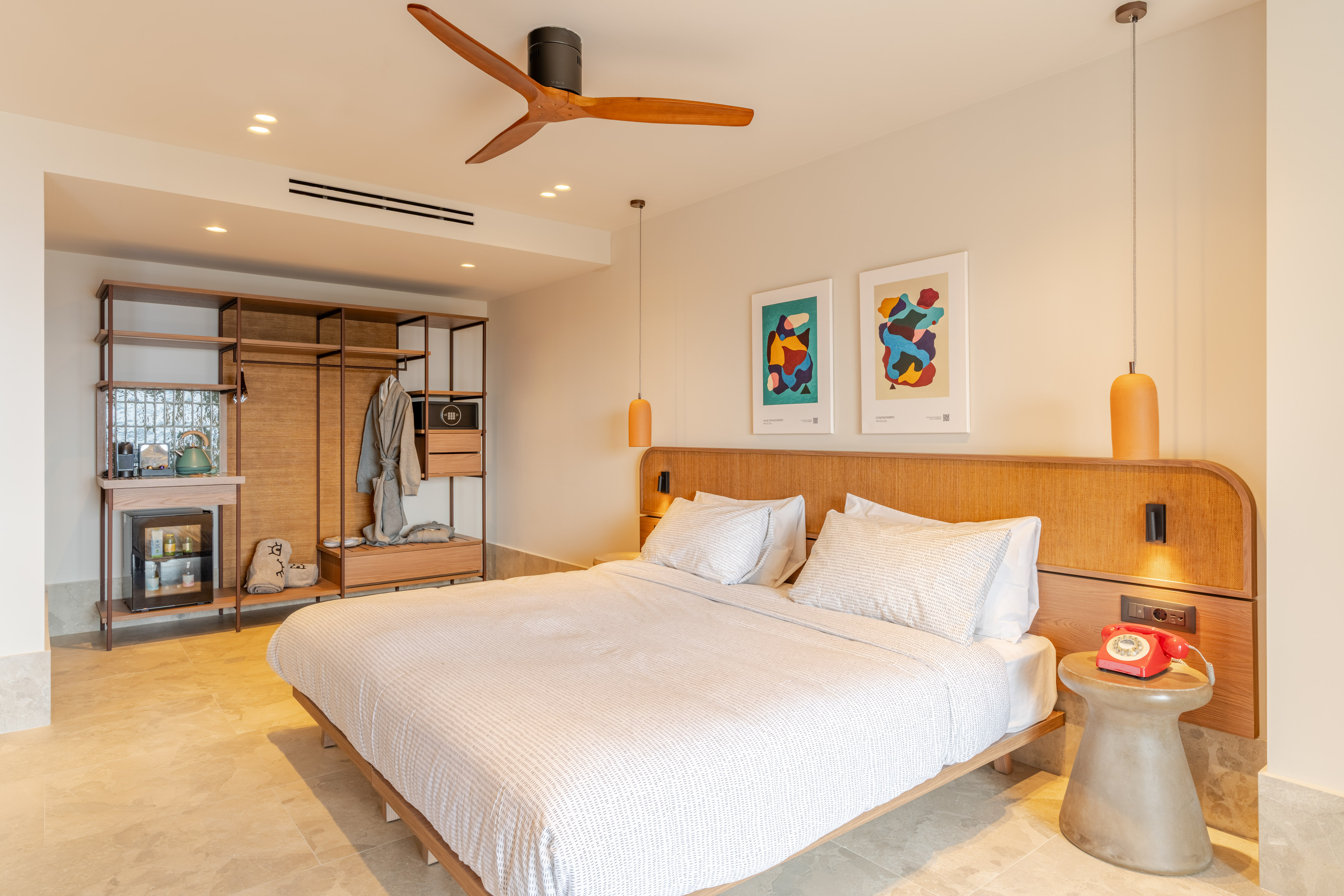 Modern hotel room with wooden bed, ceiling fan, and contemporary decor.