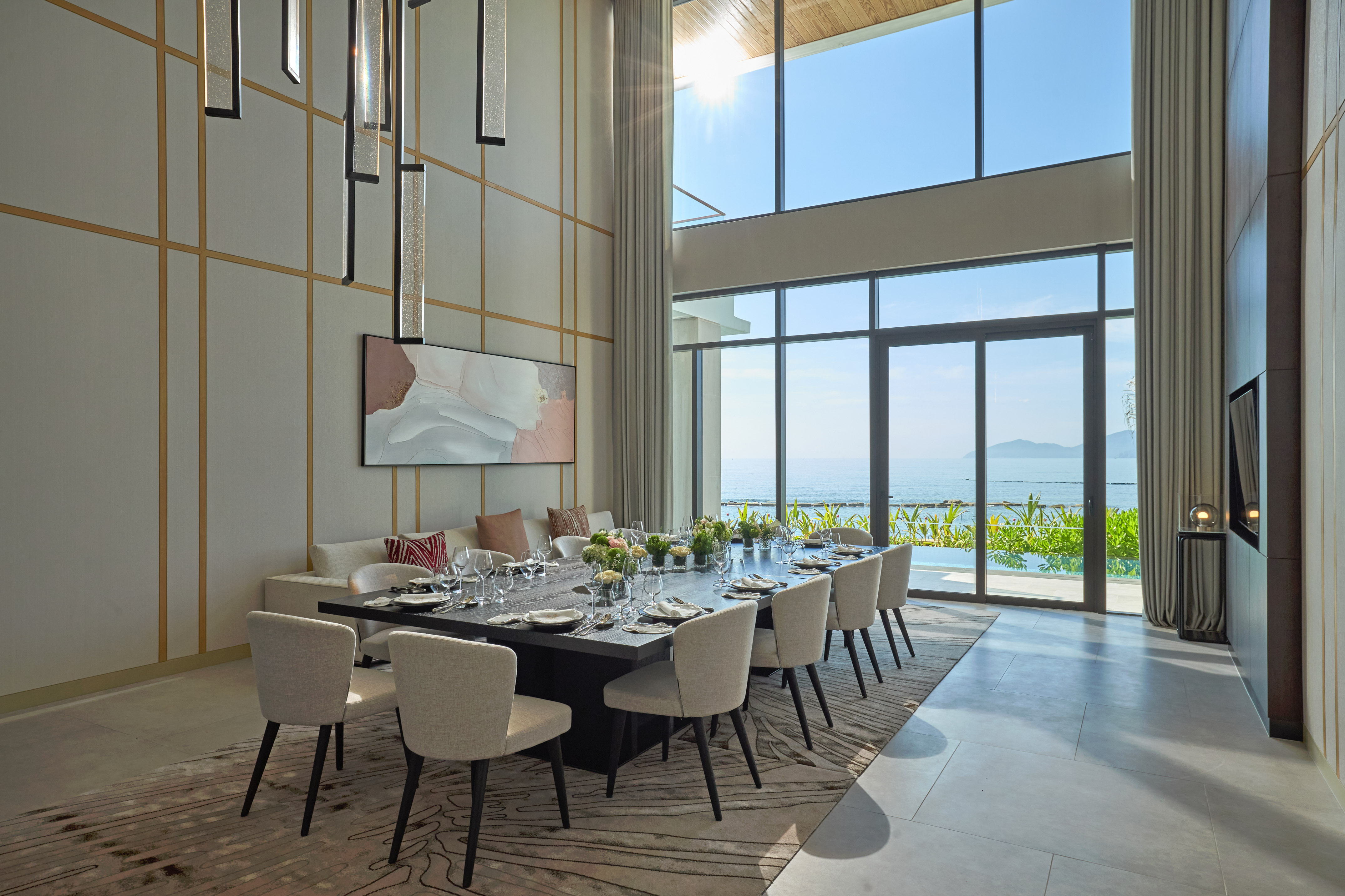 Luxurious modern dining room with ocean view, high ceilings, and large table.