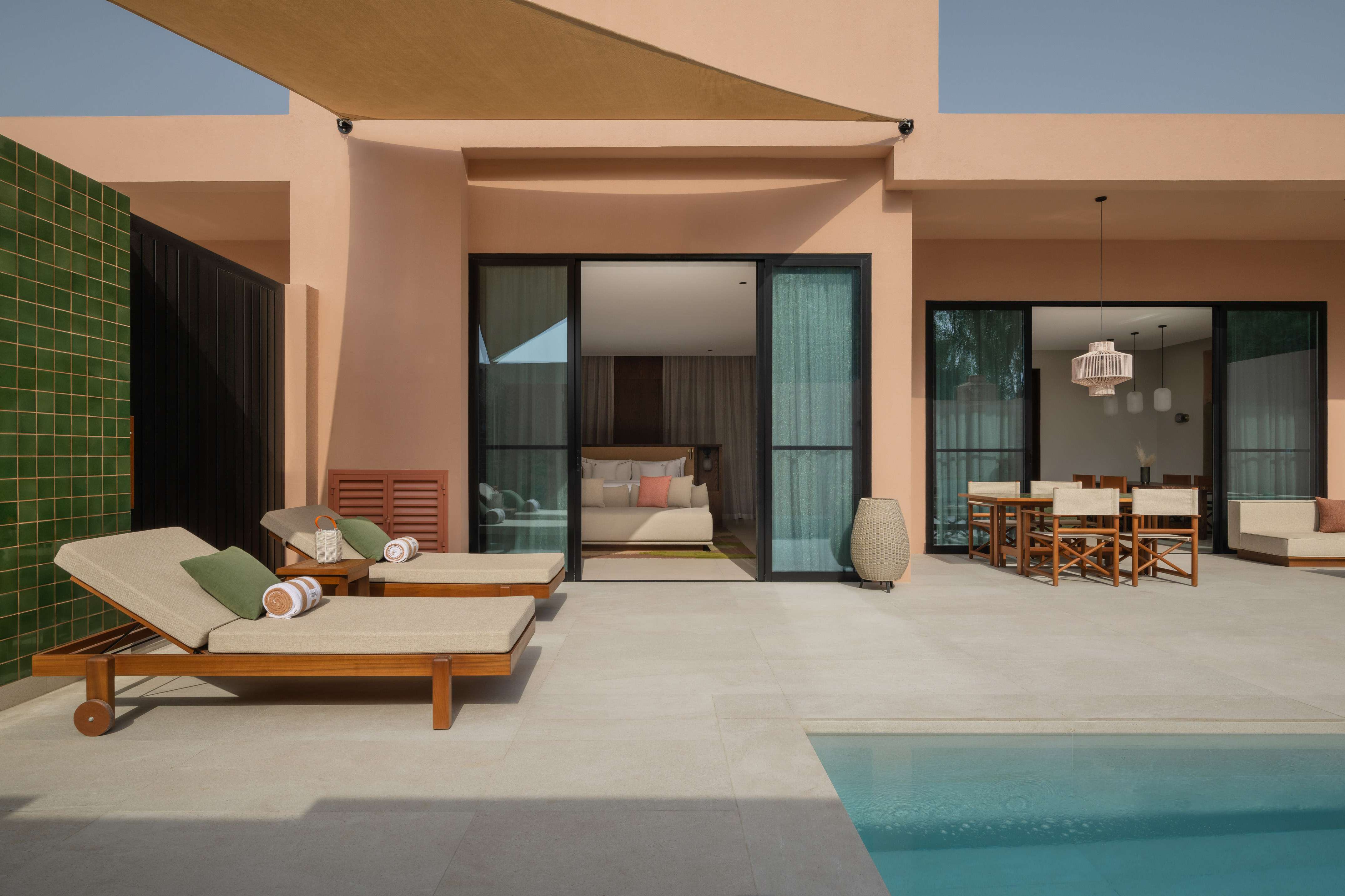 Private villa patio with pool, daybeds, and indoor/outdoor living spaces.