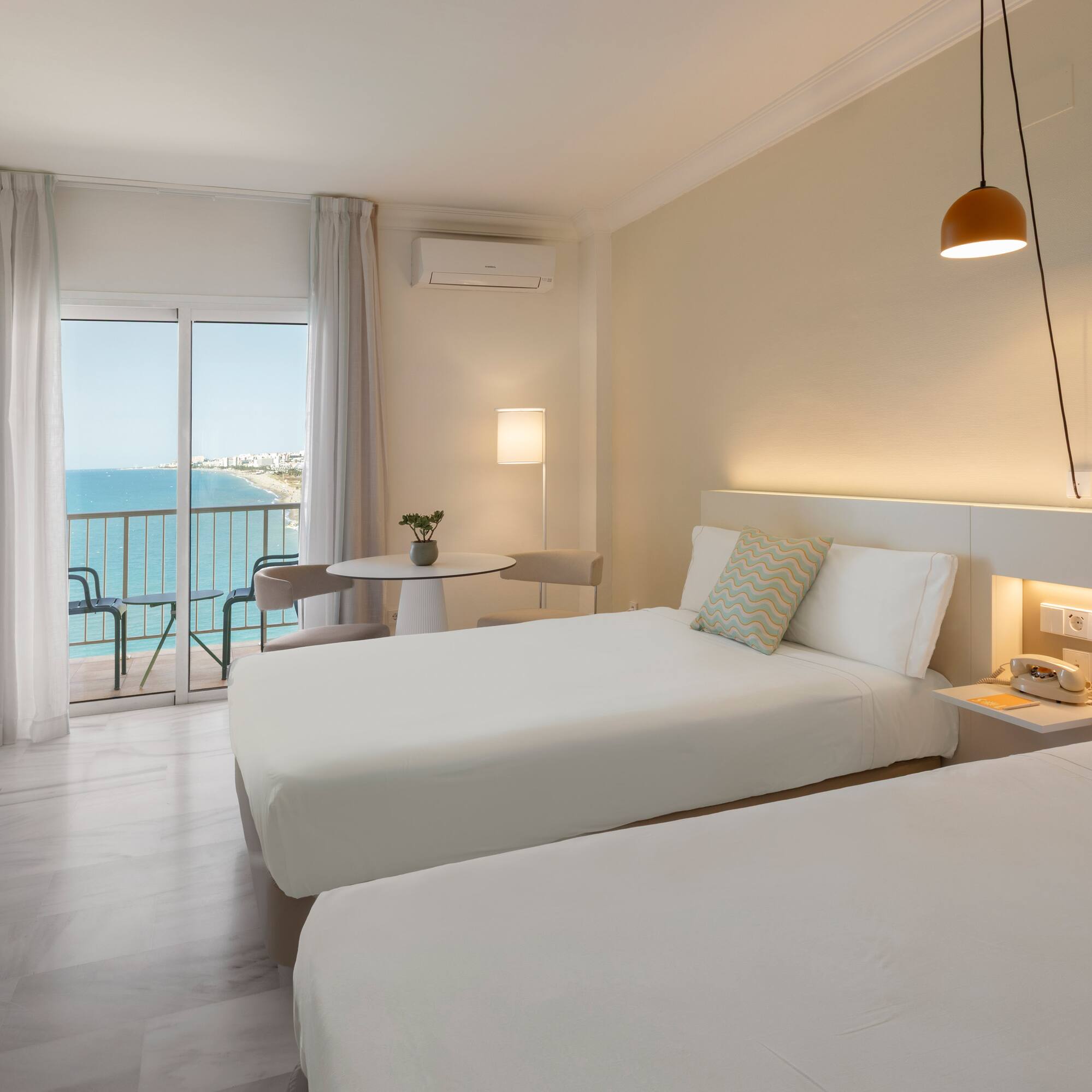 Habitación de hotel doble moderna con balcón y vistas al mar.