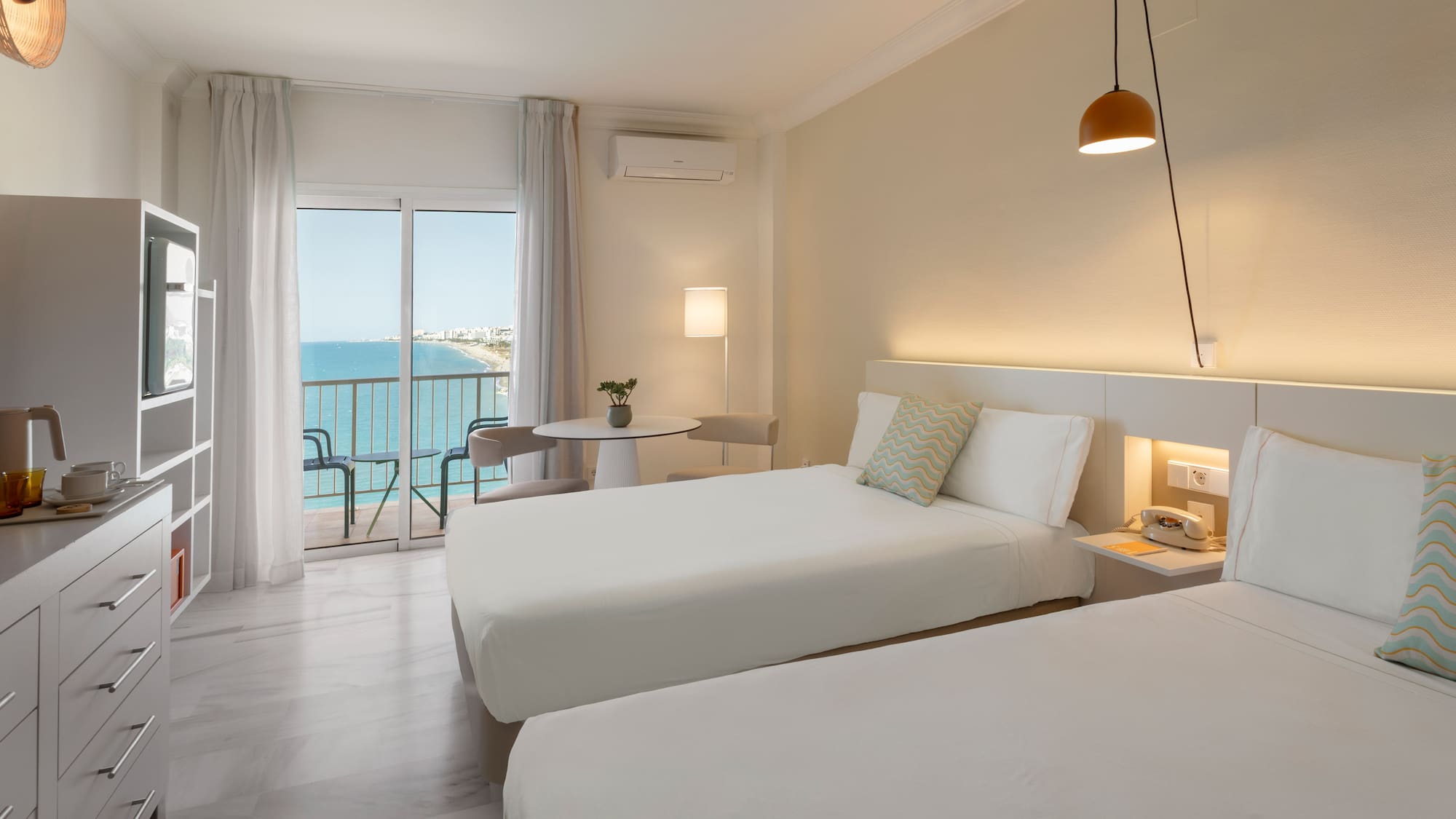 Habitación de hotel doble moderna con balcón y vistas al mar.