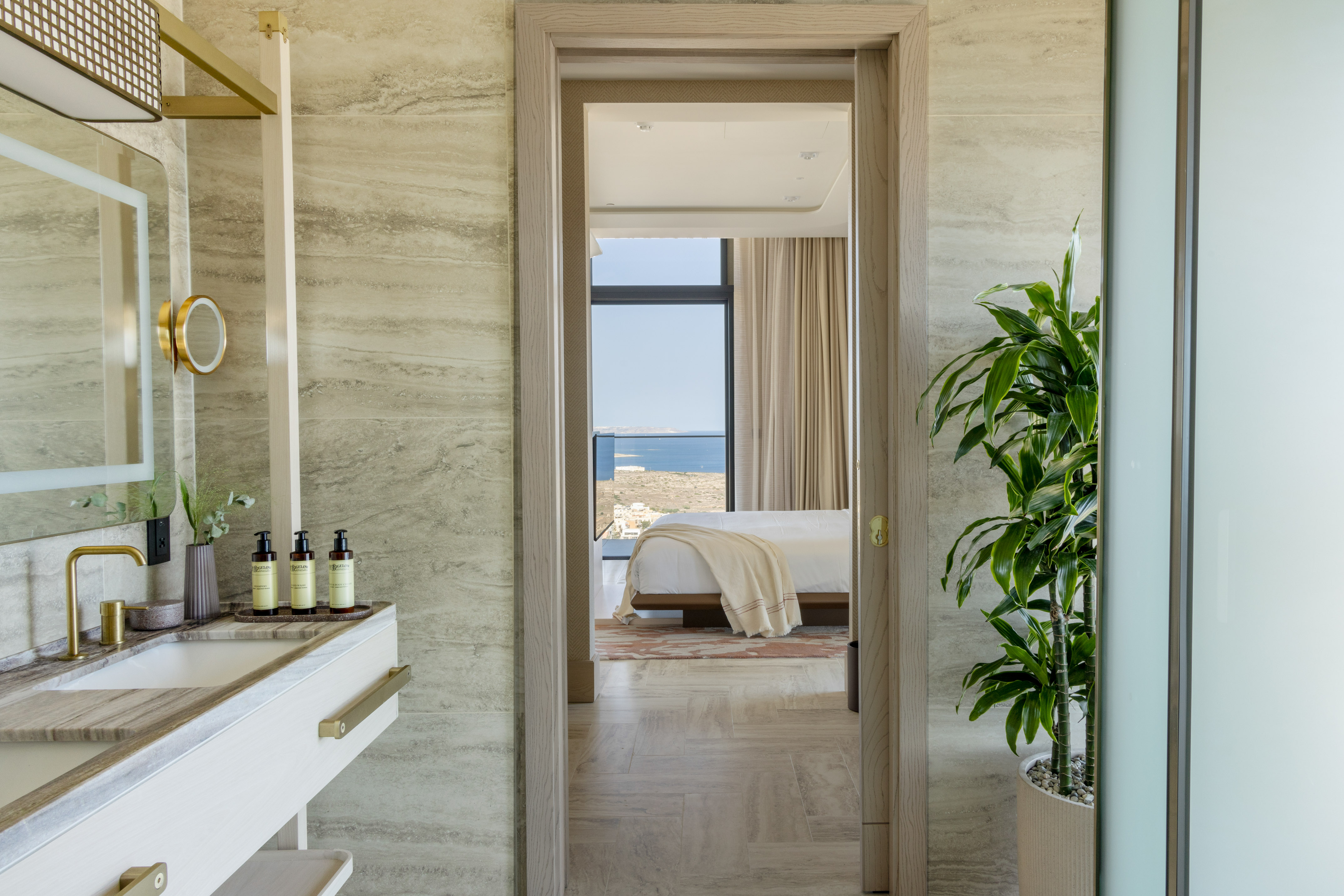Luxurious bathroom vanity, stone walls, leading to bedroom with ocean view.