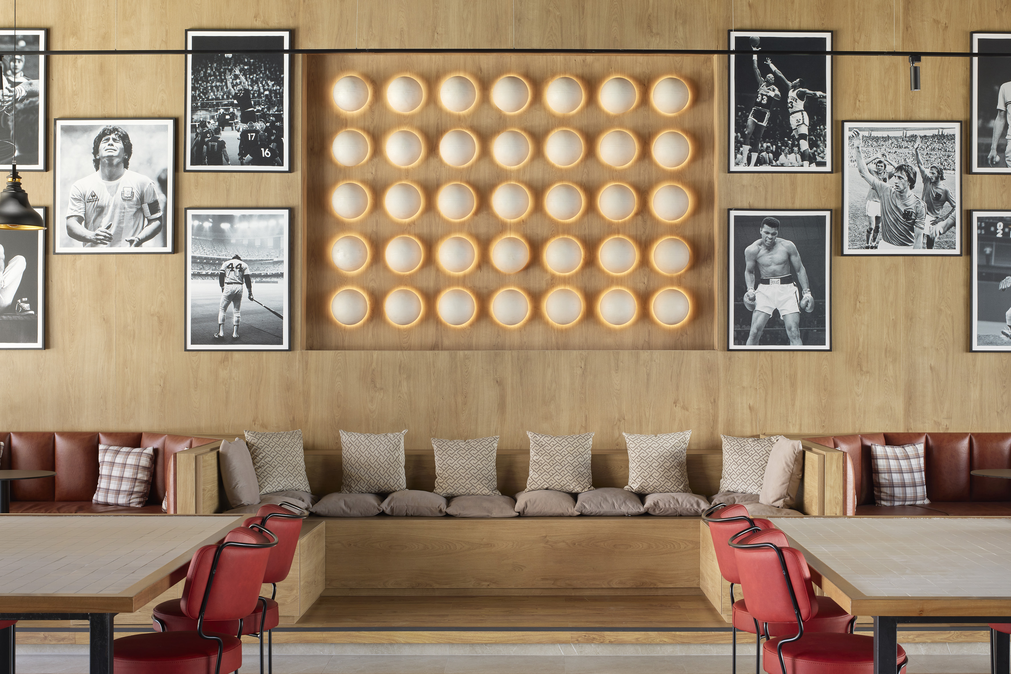 Modern sports restaurant: athlete photos, warm grid lights, wood walls, leather booths.