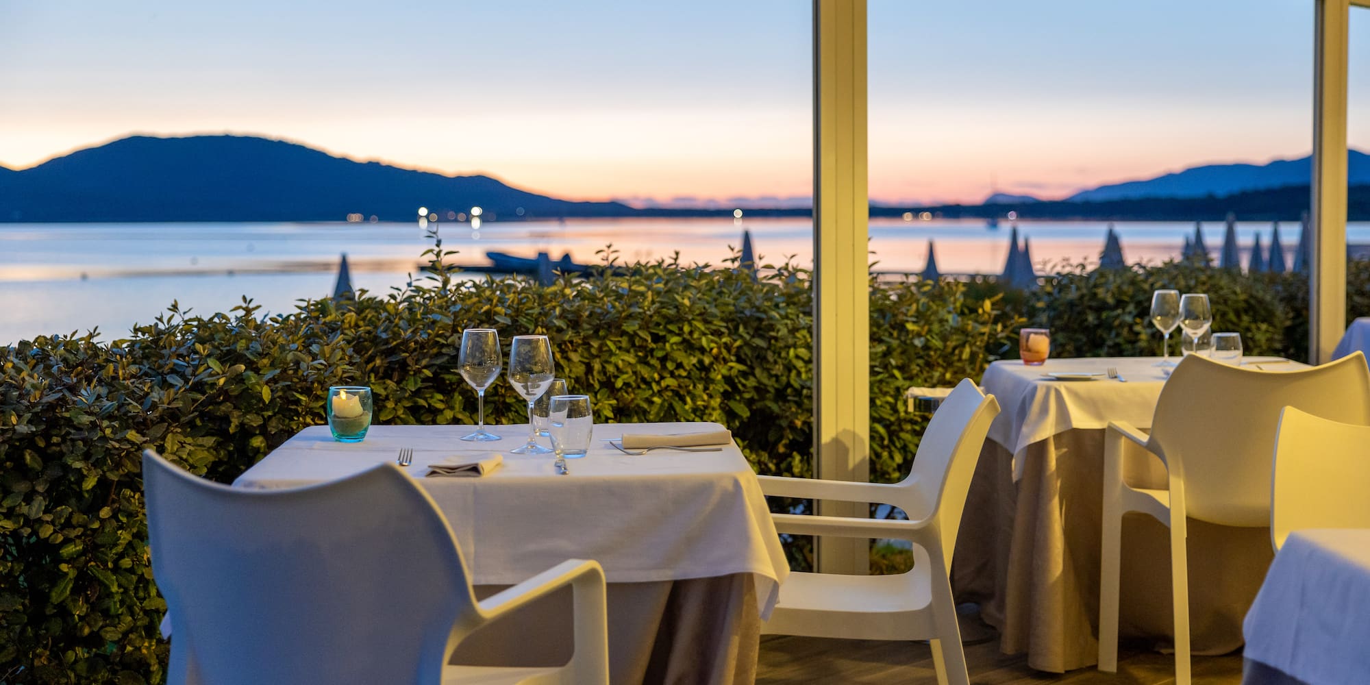 a table set up with wine glasses and a view of the water