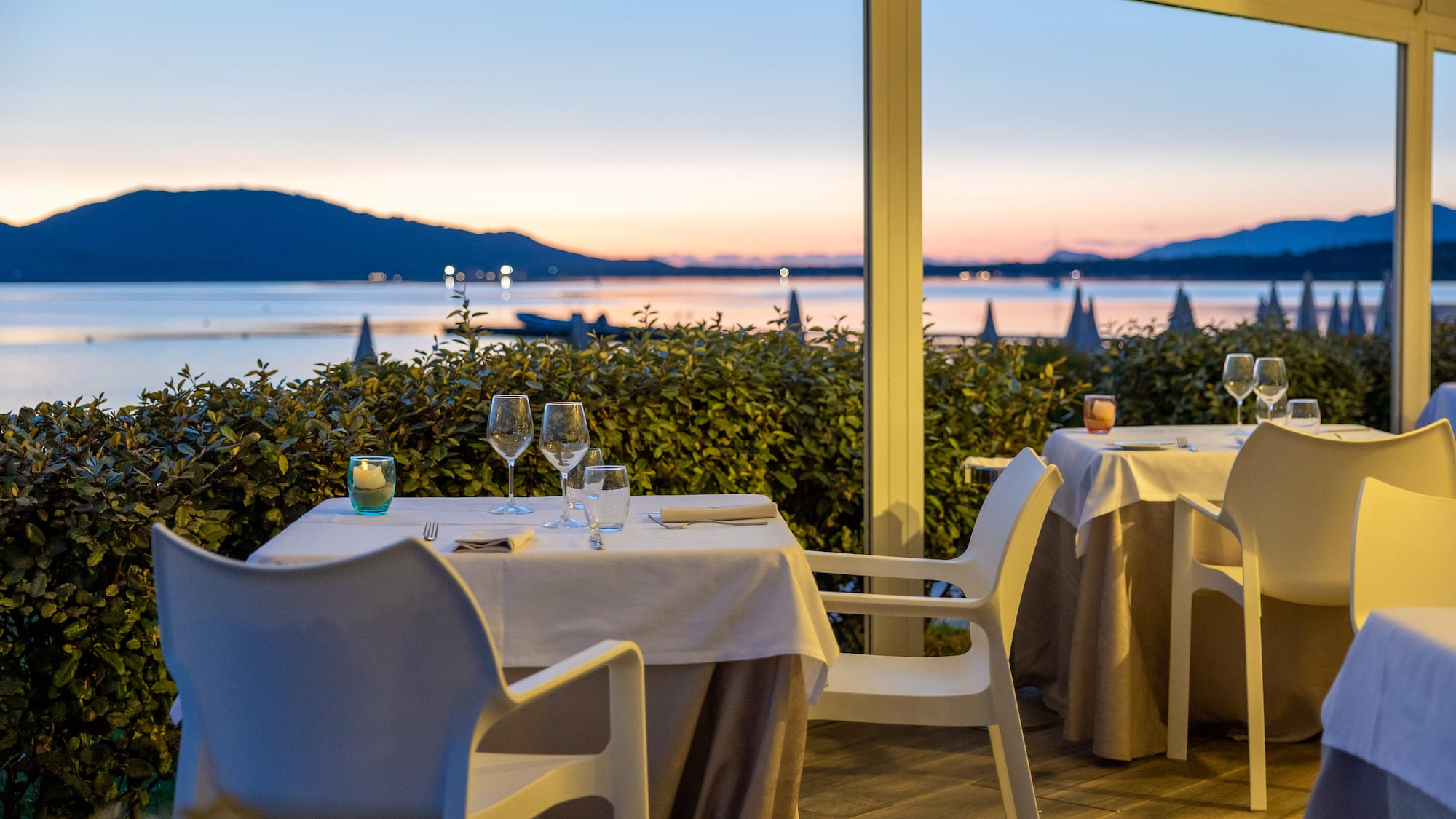 a table set up with wine glasses and a view of the water