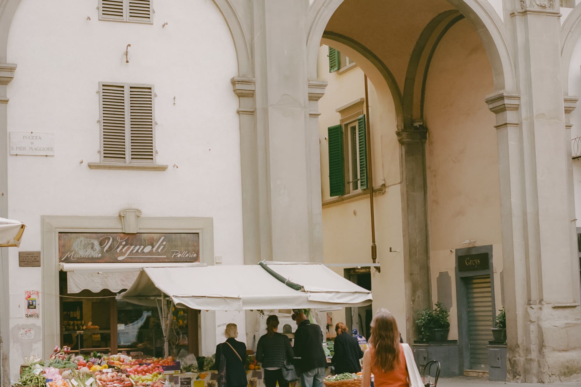 a woman walking in front of a fruit stand
