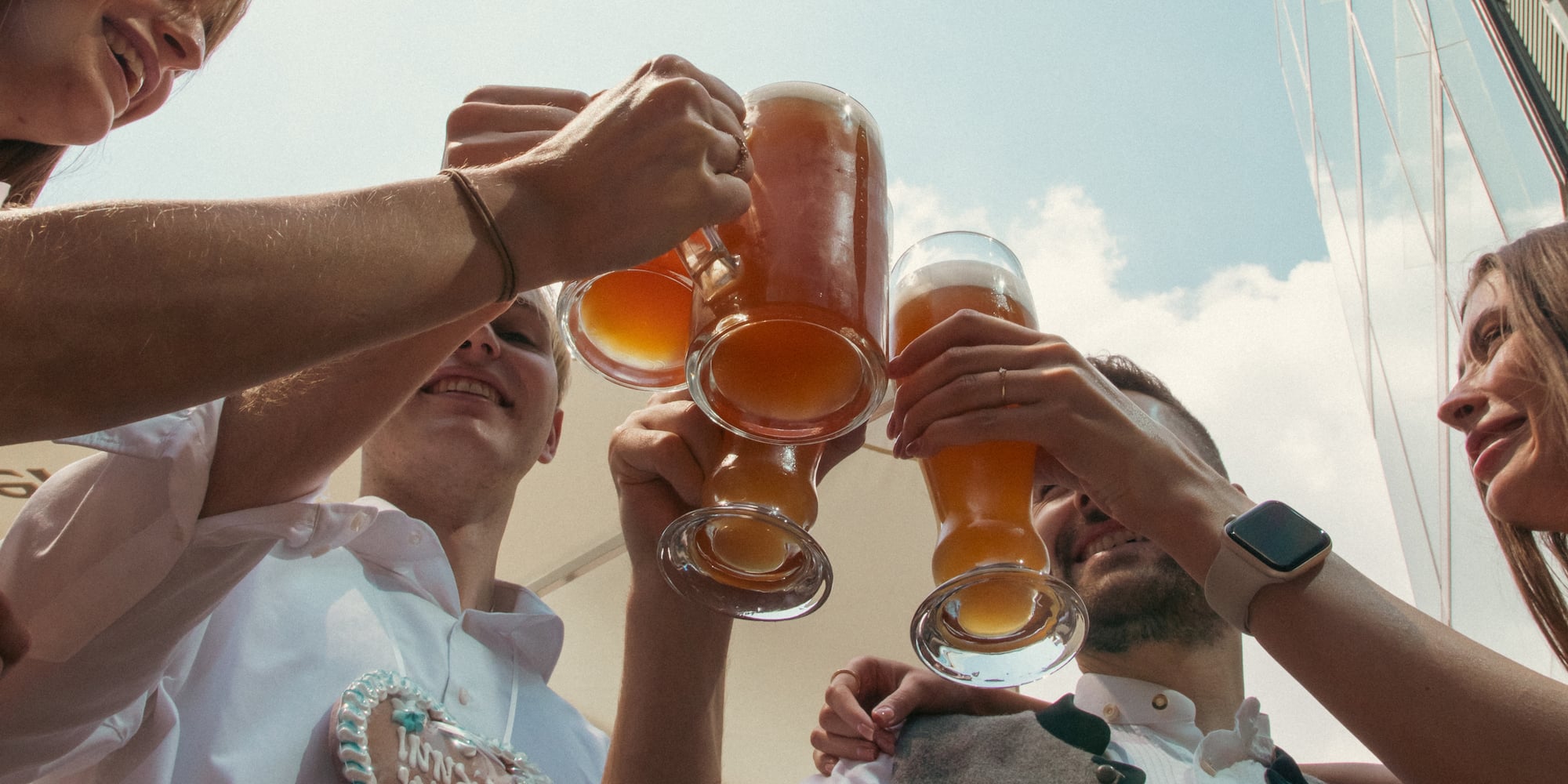 Friends in trachten raising beer steins, with 'Wiesn 24' gingerbread heart.