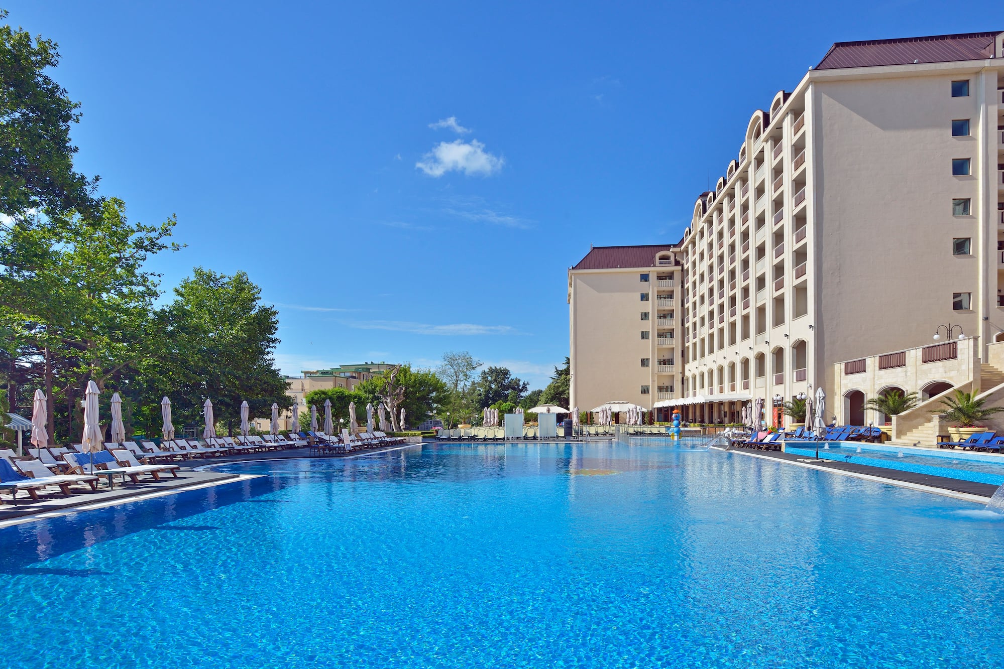 a large pool with chairs and umbrellas in front of a building