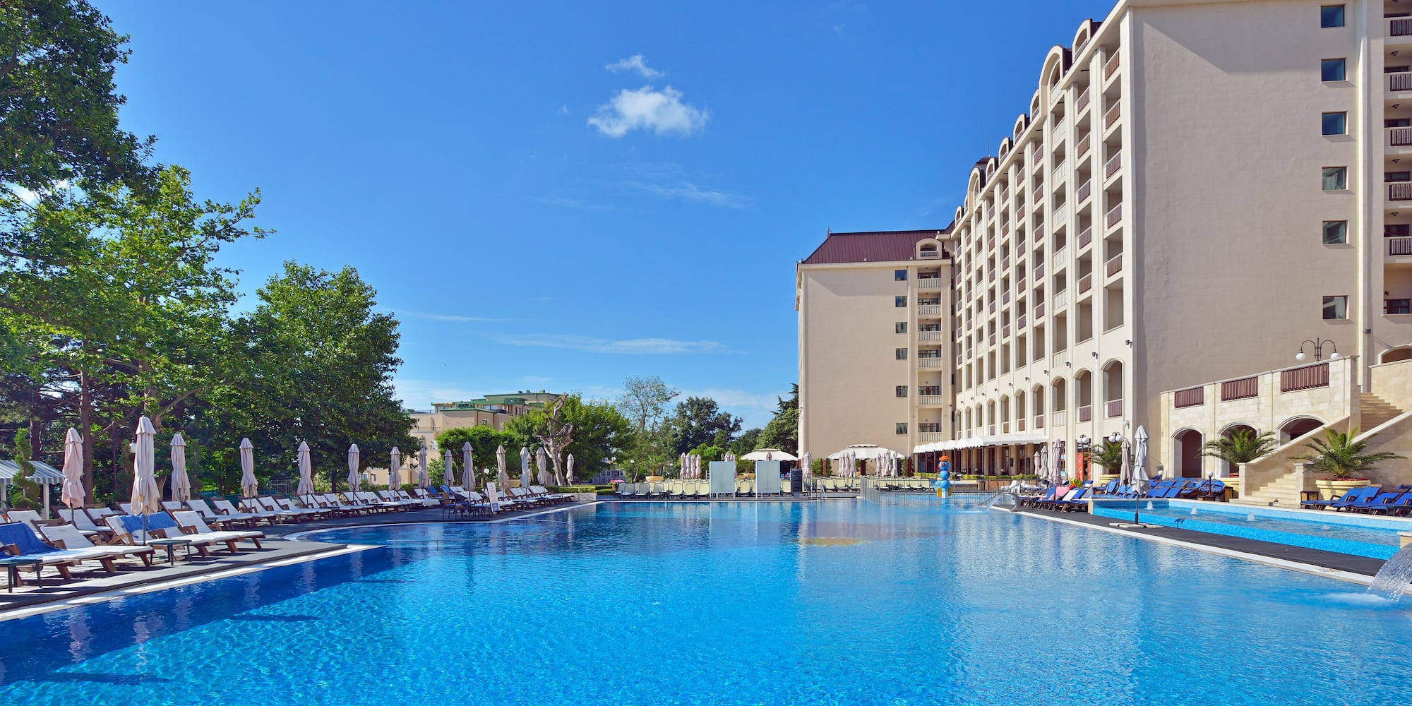 a large pool with chairs and umbrellas in front of a building
