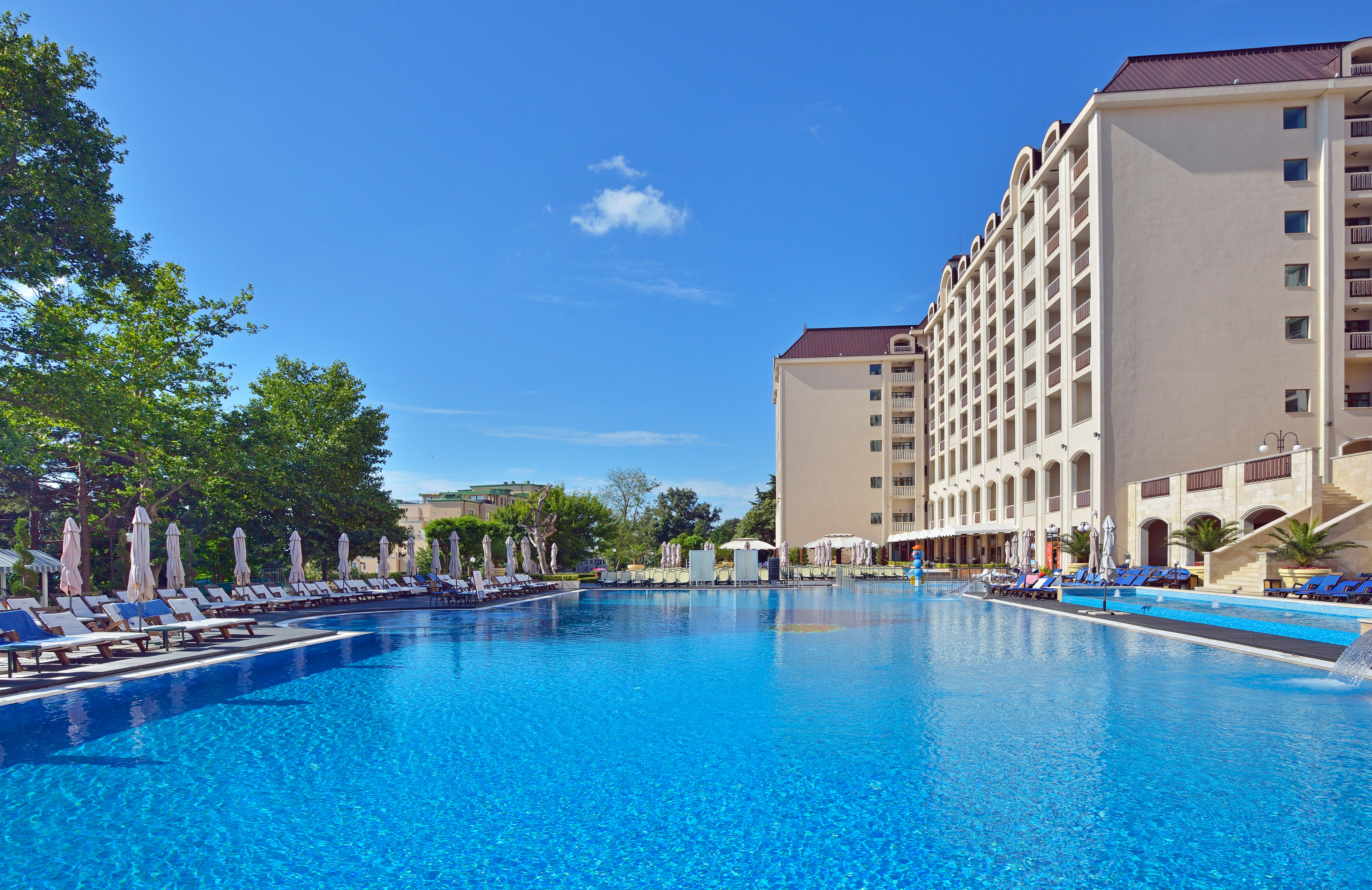 a large pool with chairs and umbrellas in front of a building