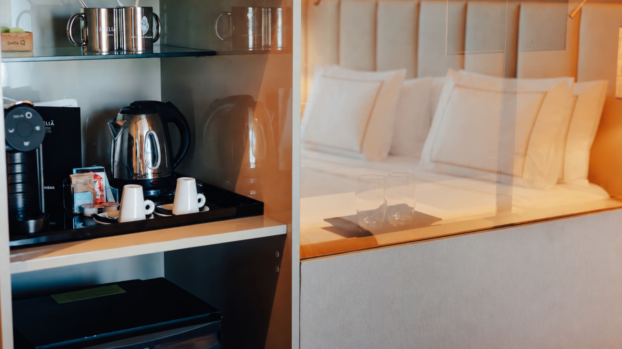 Hotel room with coffee machine, kettle, minibar, and a comfortable bed.