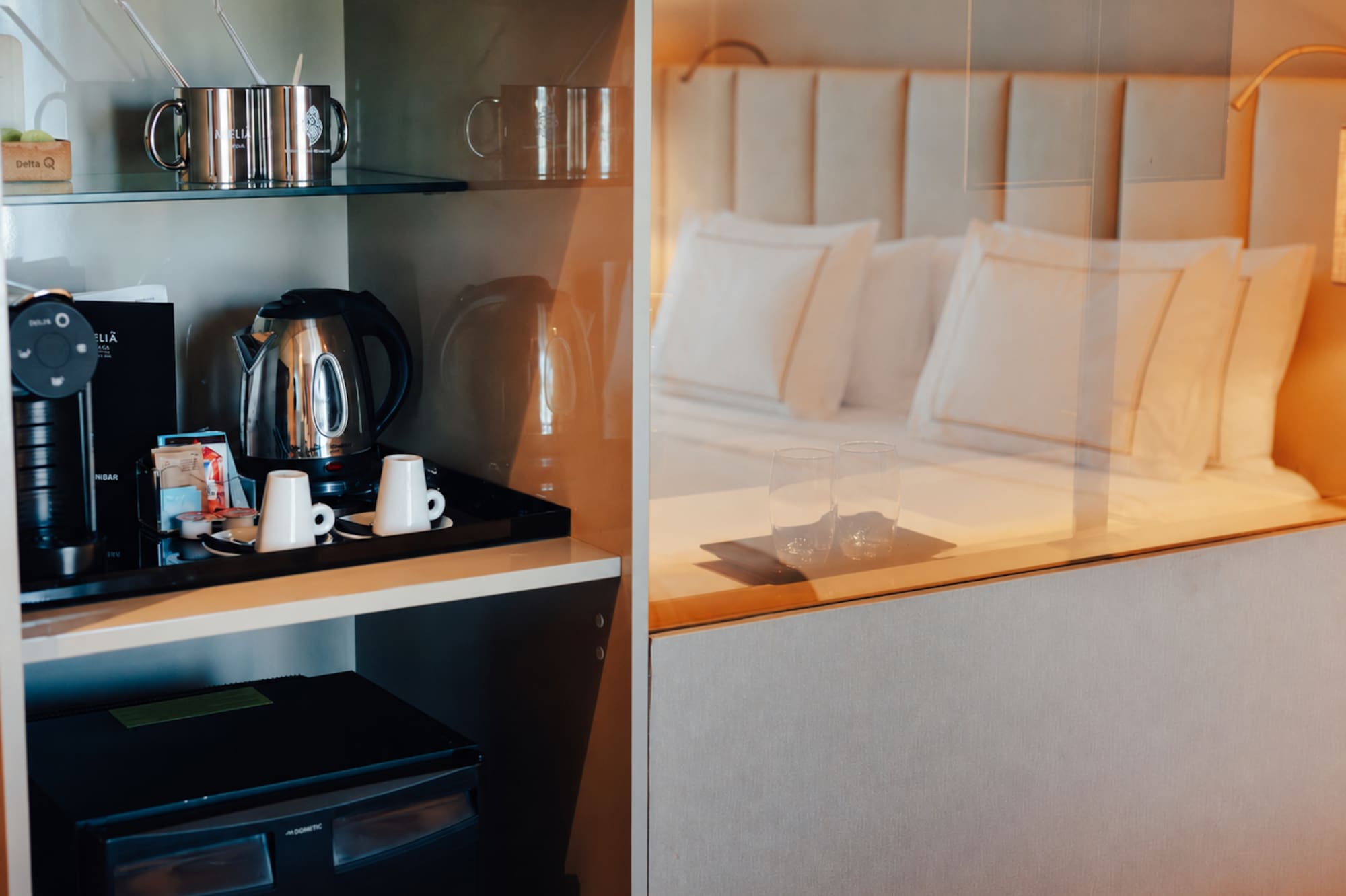 Hotel room with coffee machine, kettle, minibar, and a comfortable bed.