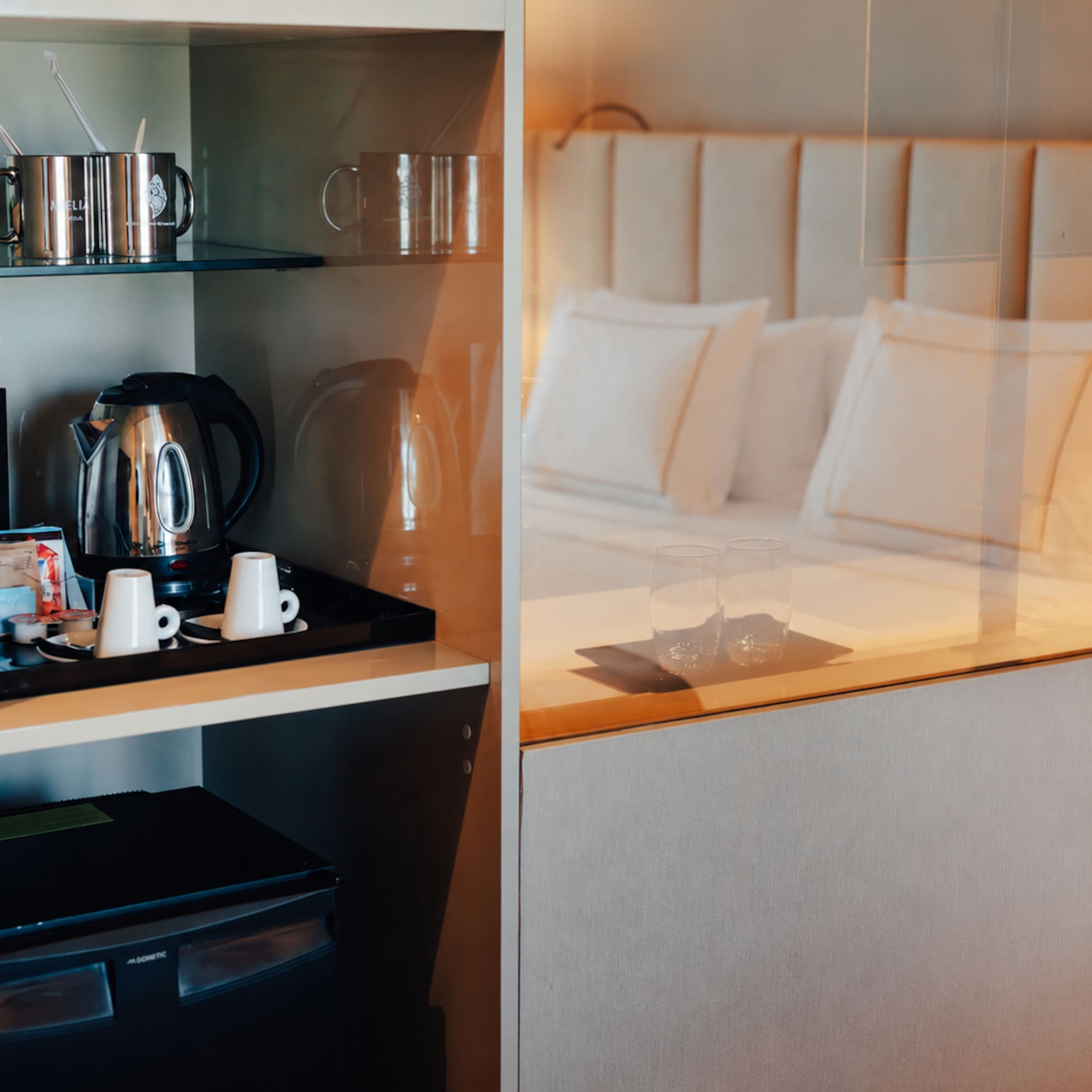 Hotel room with coffee machine, kettle, minibar, and a comfortable bed.
