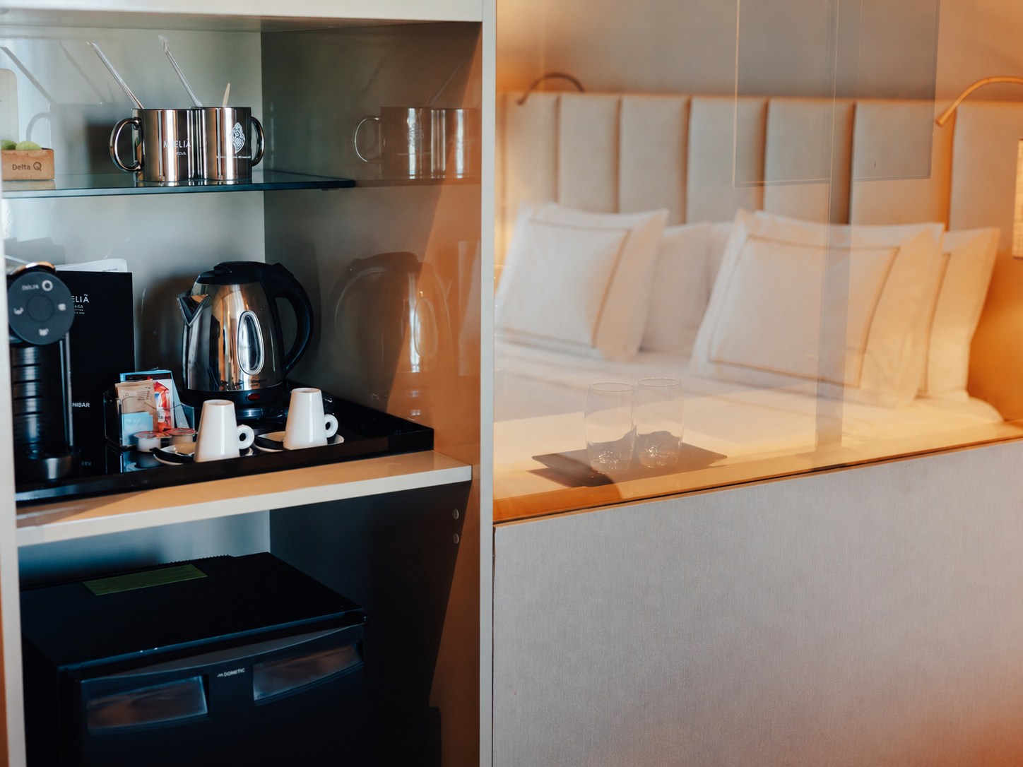 Hotel room with coffee machine, kettle, minibar, and a comfortable bed.