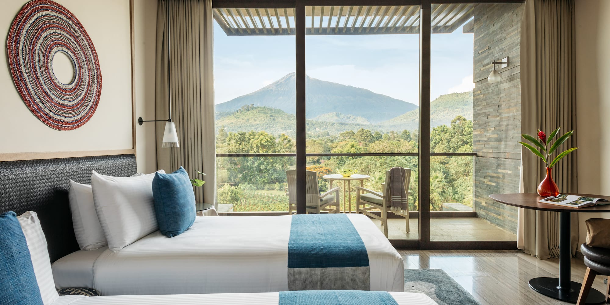 two beds in a room with a view of mountains and trees