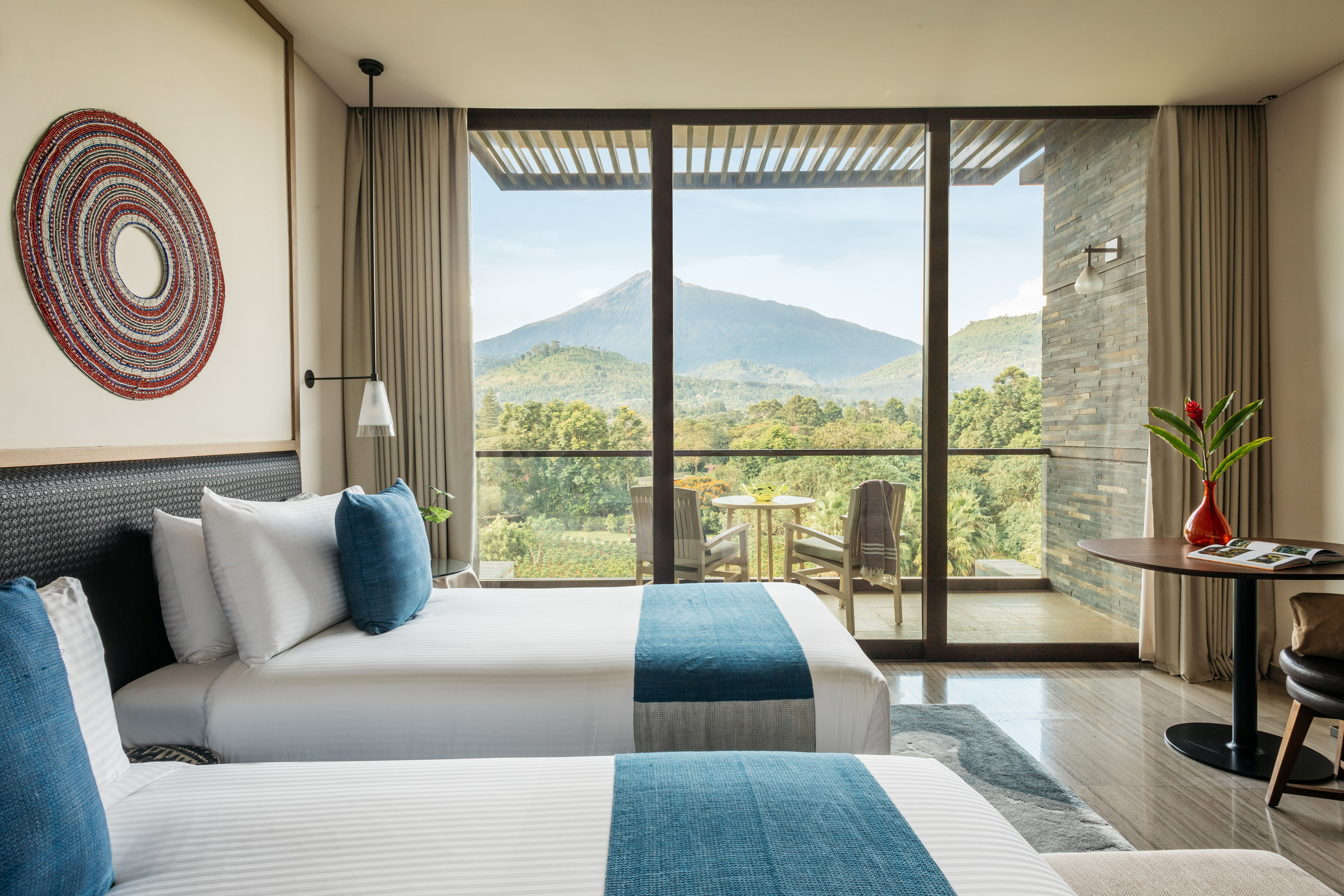 two beds in a room with a view of mountains and trees