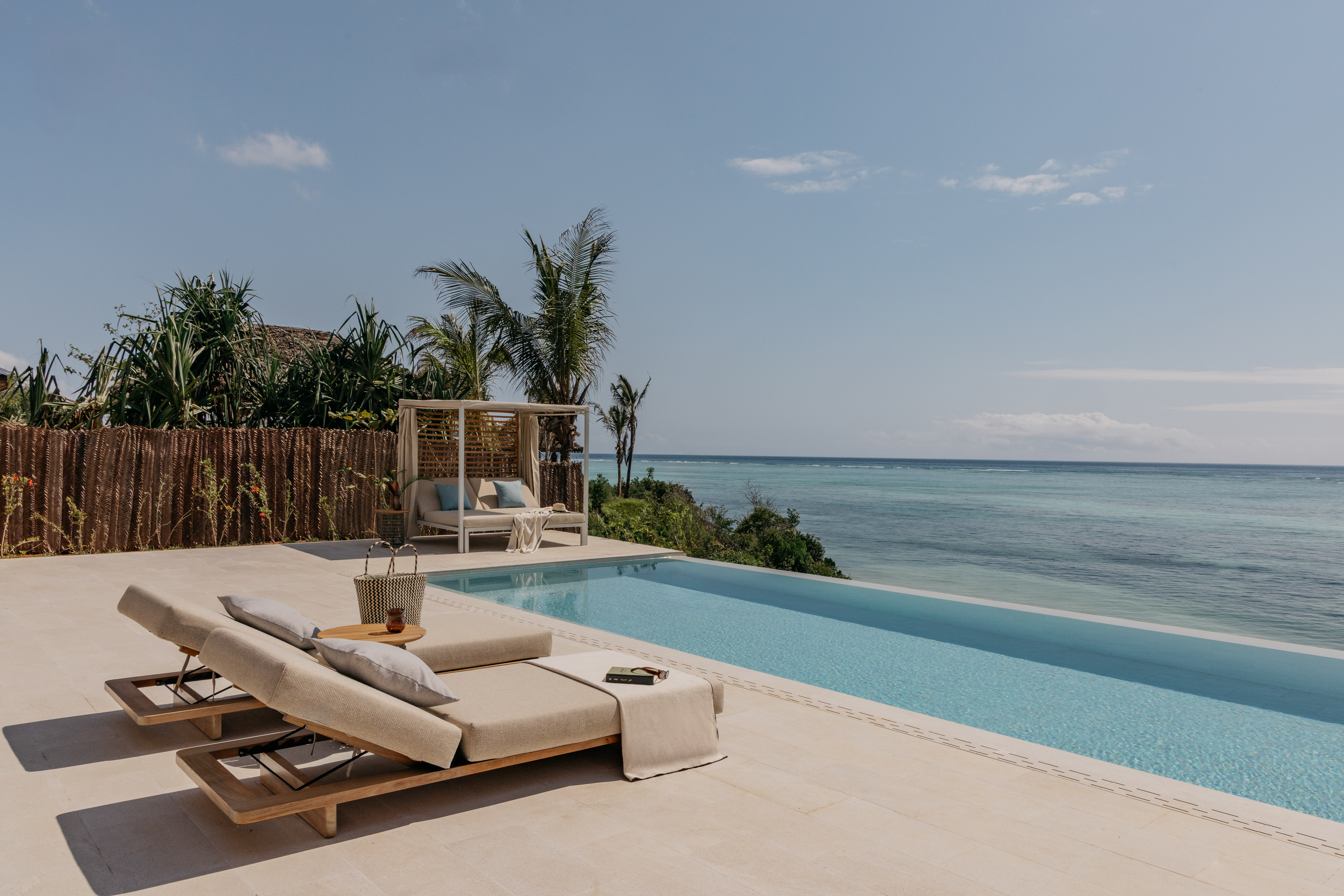 Luxury infinity pool with ocean view, comfortable lounge chairs and a daybed.