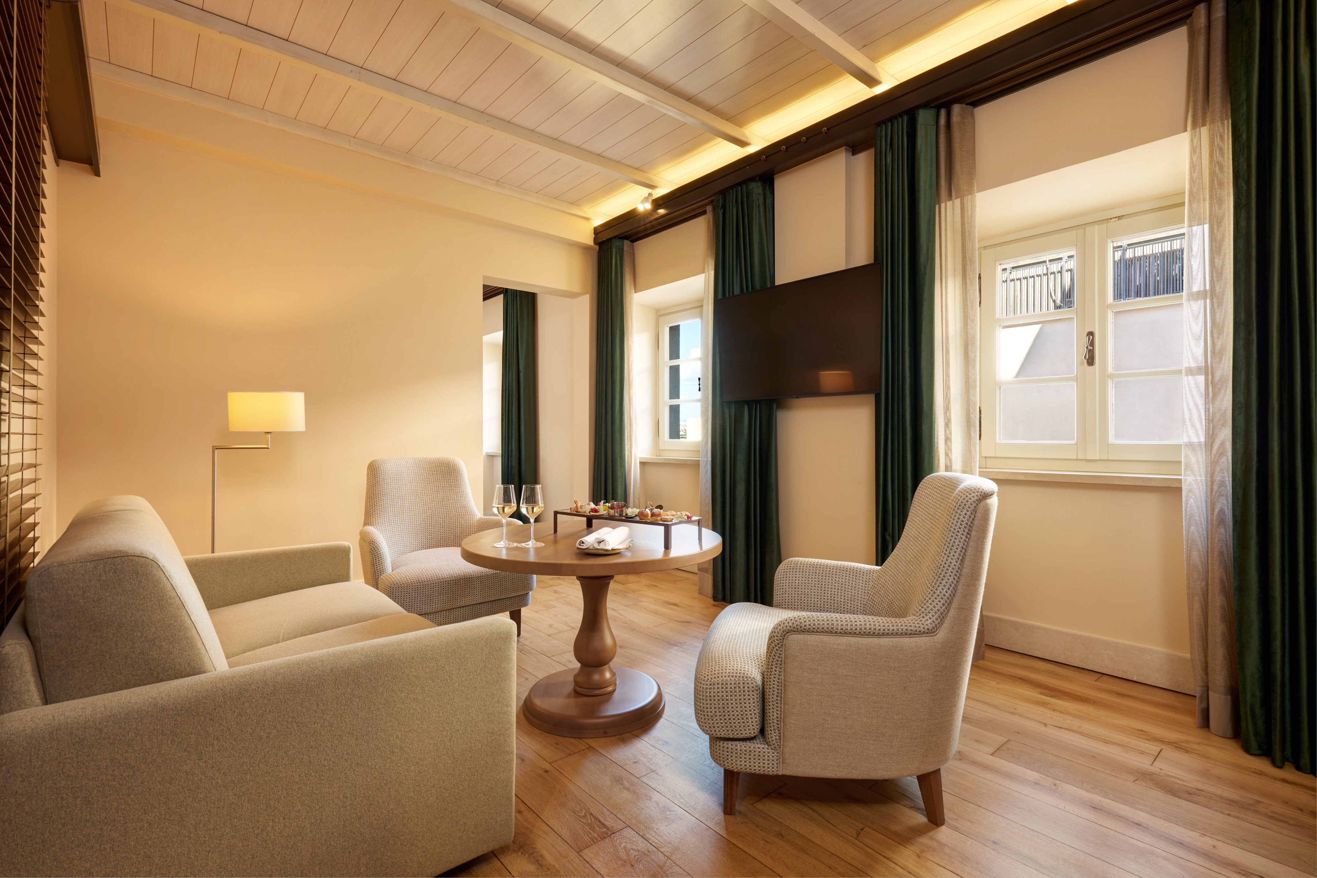 Hotel suite living room with comfortable seating, wood floor, snacks, and TV.
