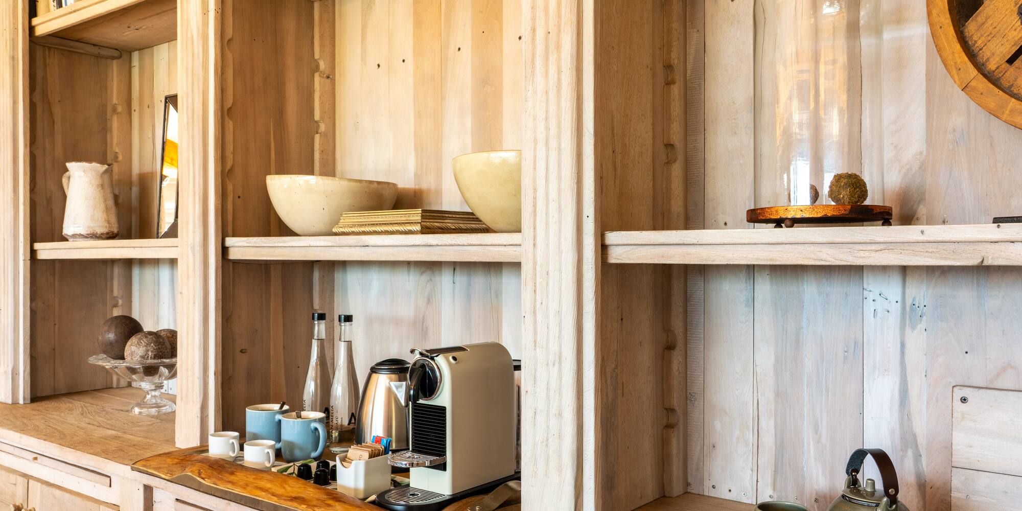 a shelf with a coffee maker and cups on it