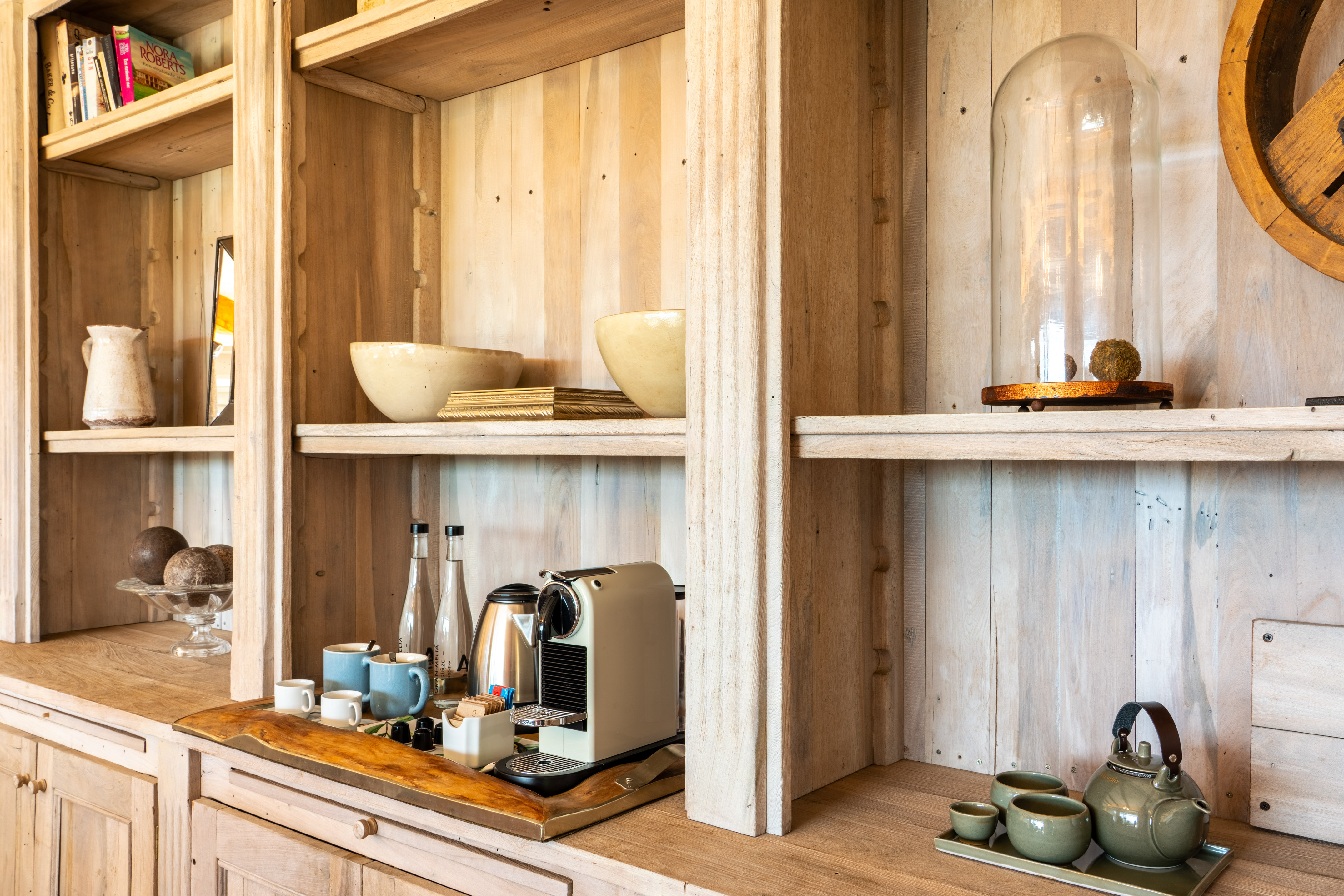 Rustic wooden shelving with a coffee machine, tea set, books, and decor.