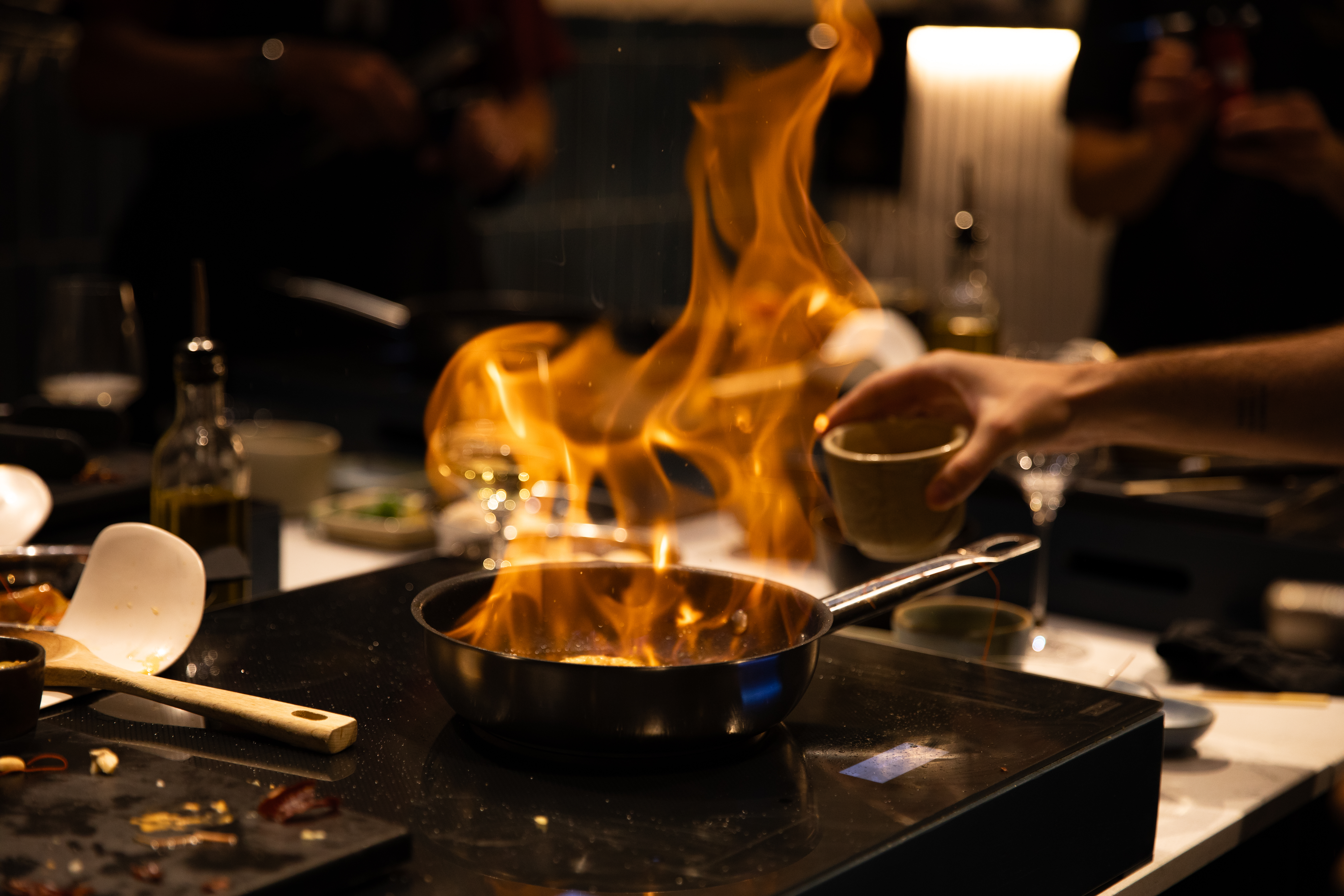 a person pouring a cup into a pan on fire