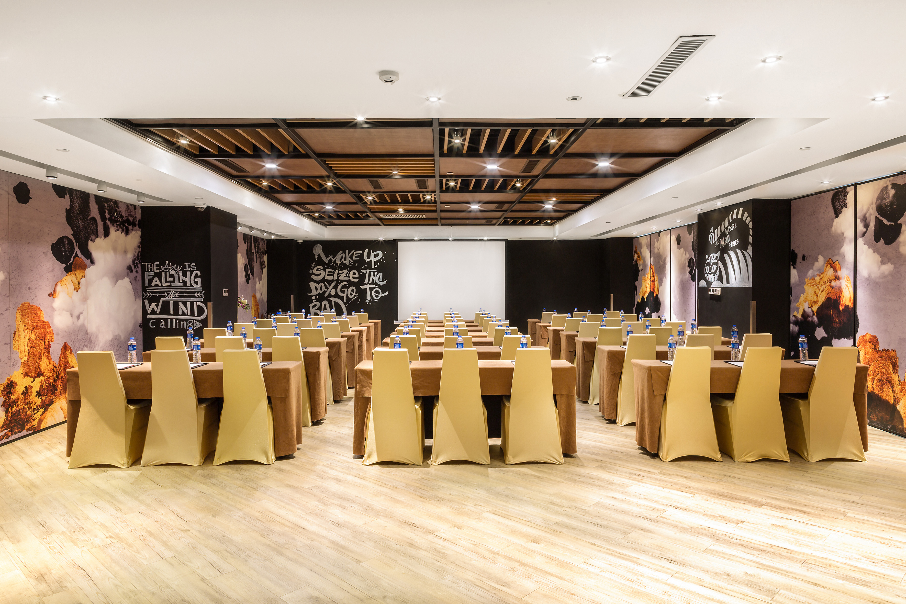 Conference room with gold chairs, projector screen, and graphic walls.