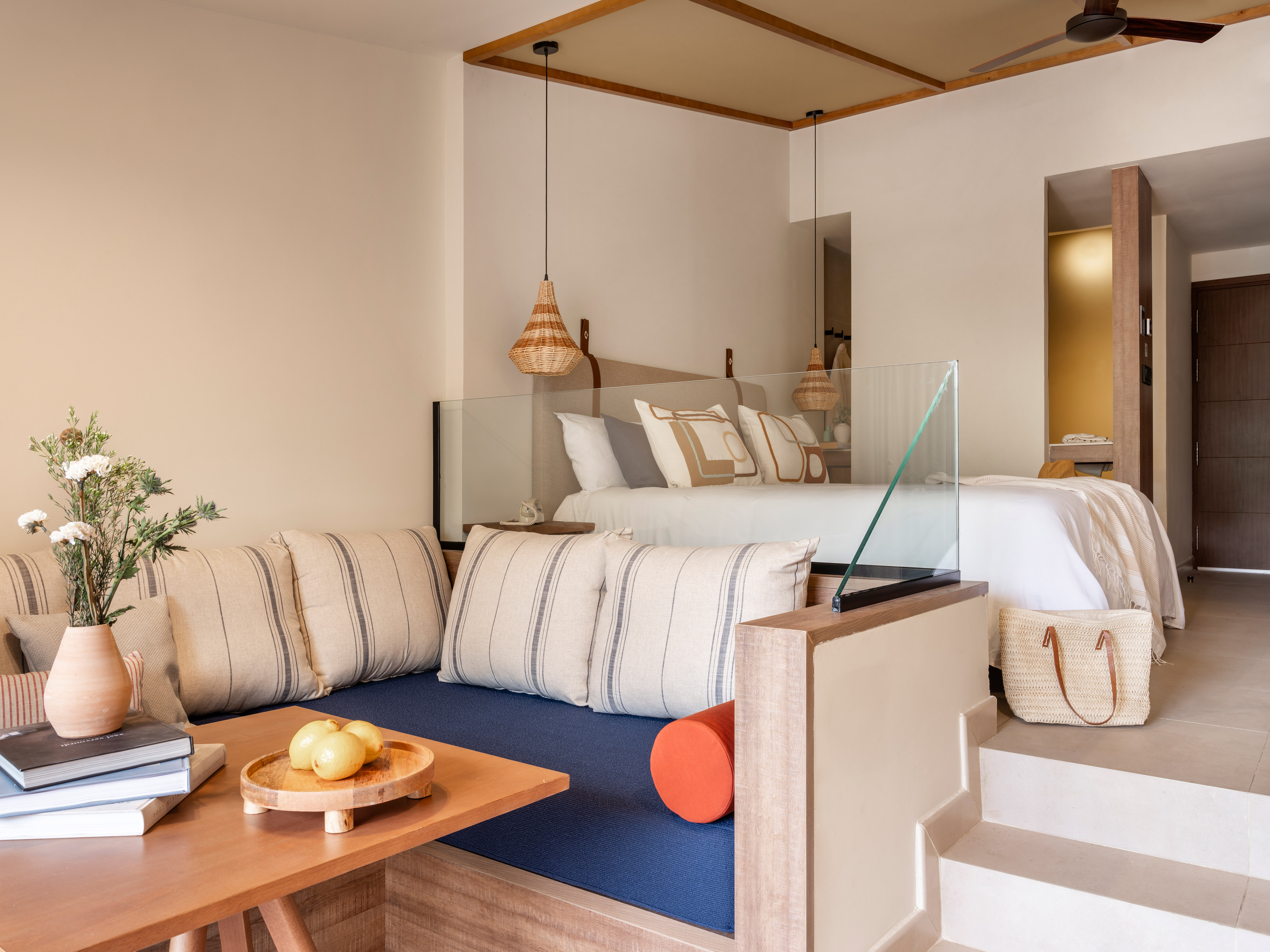 Split-level hotel suite: bed, daybed lounge, natural woven lights, modern decor.