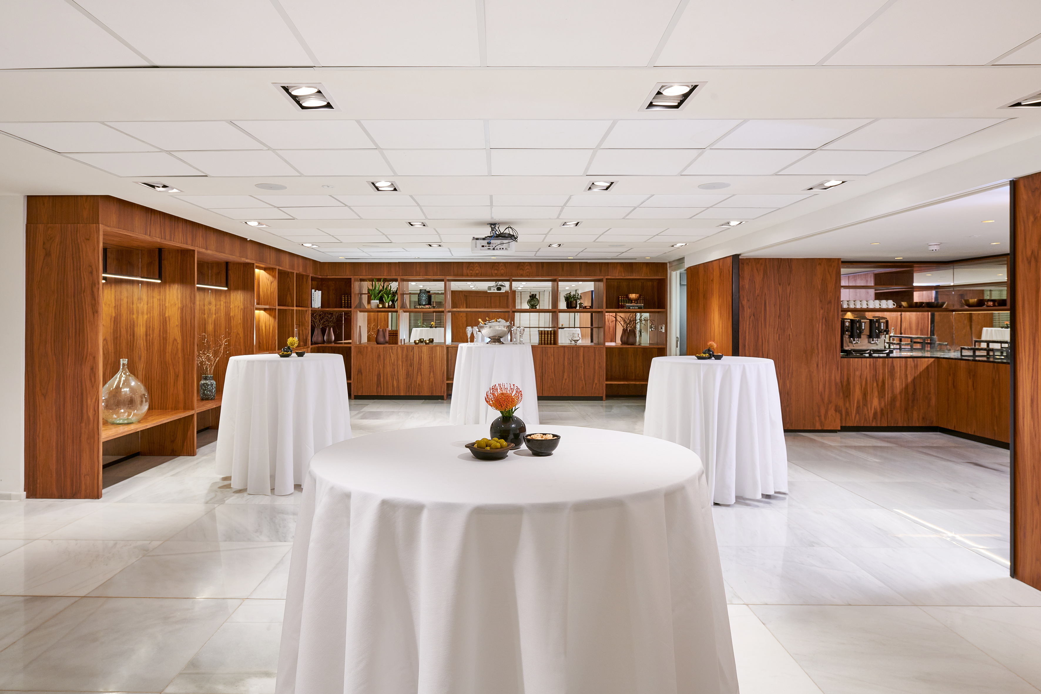 Modern reception space with high-top tables, wooden decor, and marble floor.