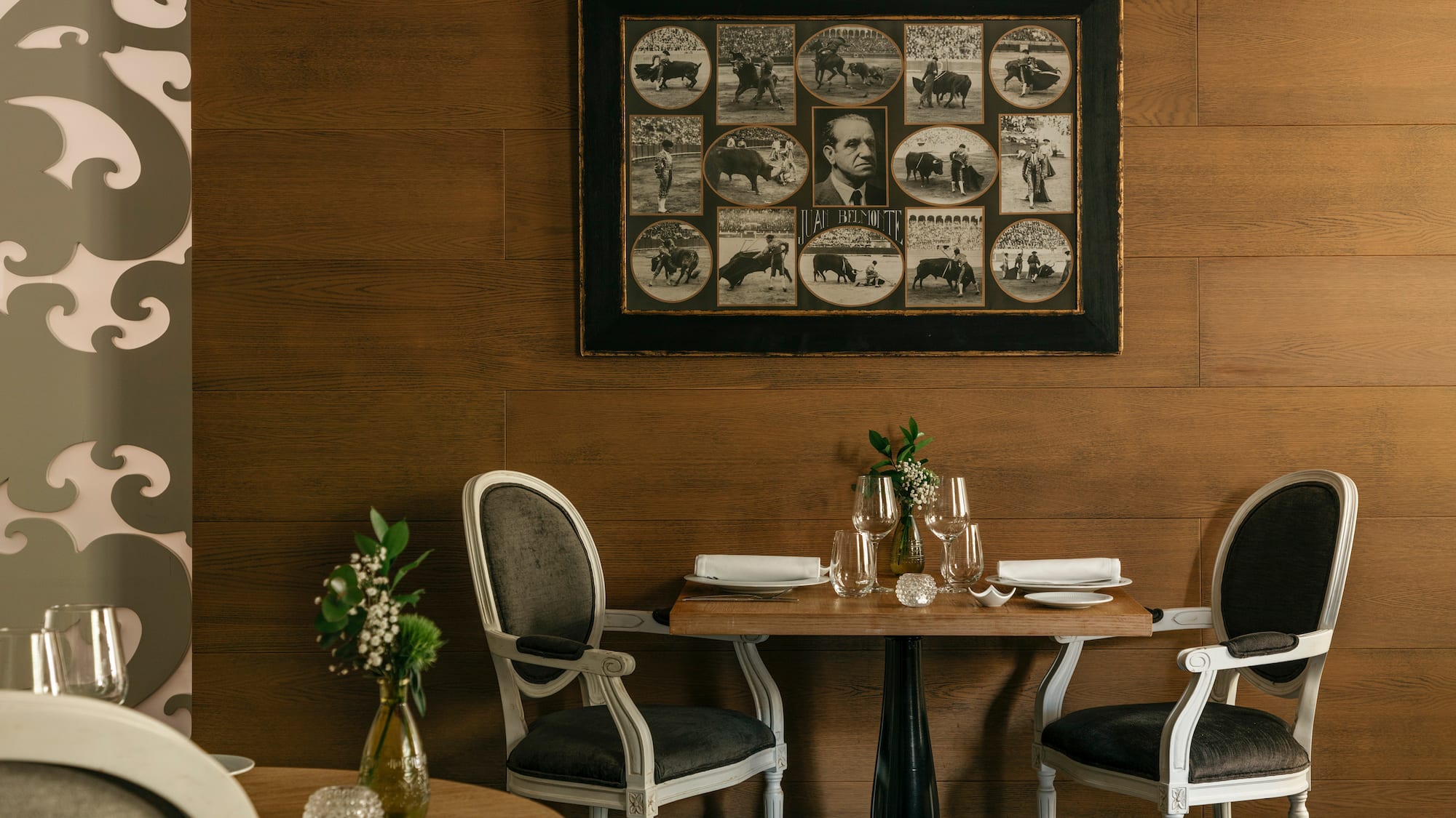 Restaurante elegante con pared de madera, mesas y collage taurino de Belmonte.