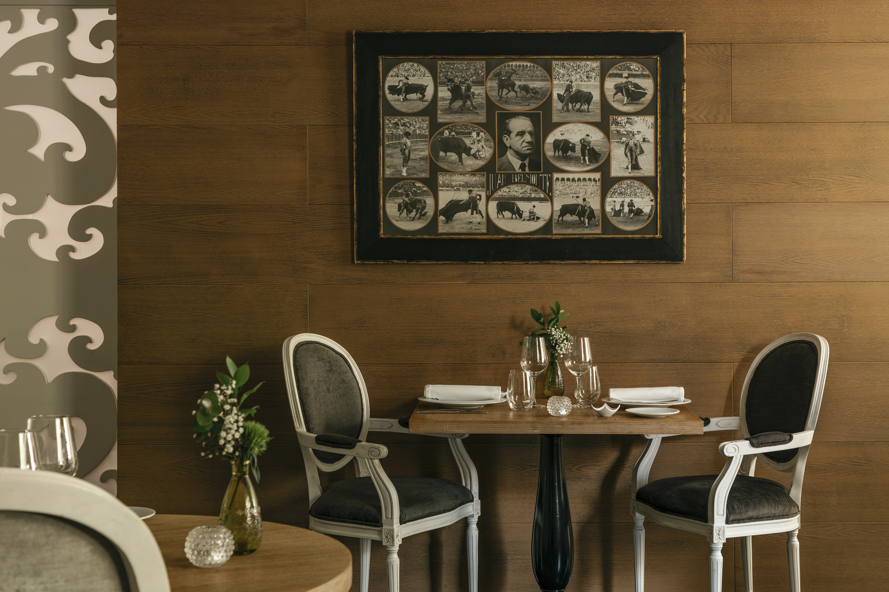 Restaurante elegante con pared de madera, mesas y collage taurino de Belmonte.