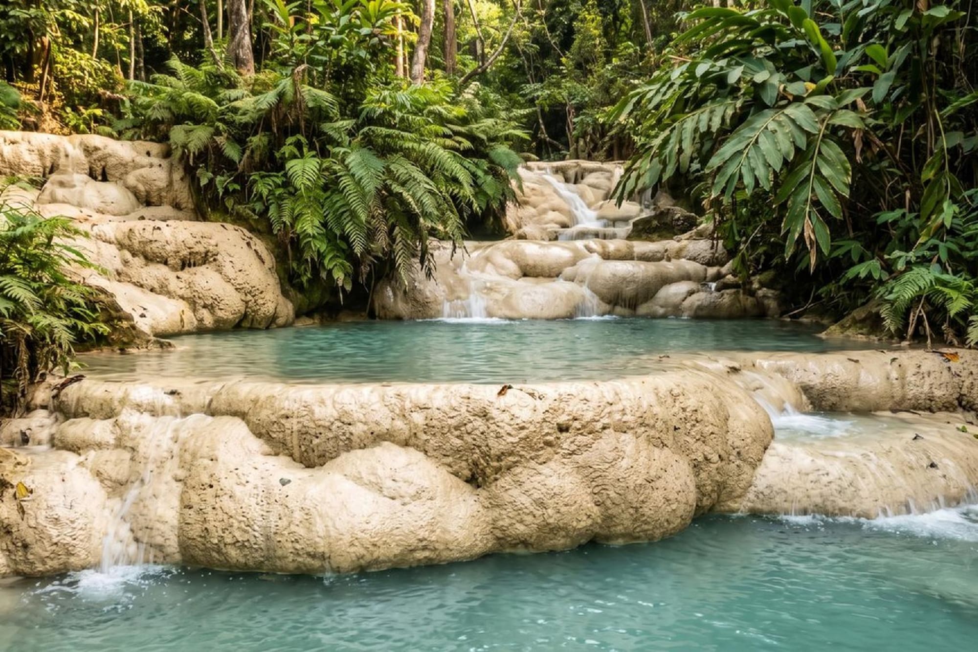 Tiered waterfall with turquoise pools and lush jungle foliage.