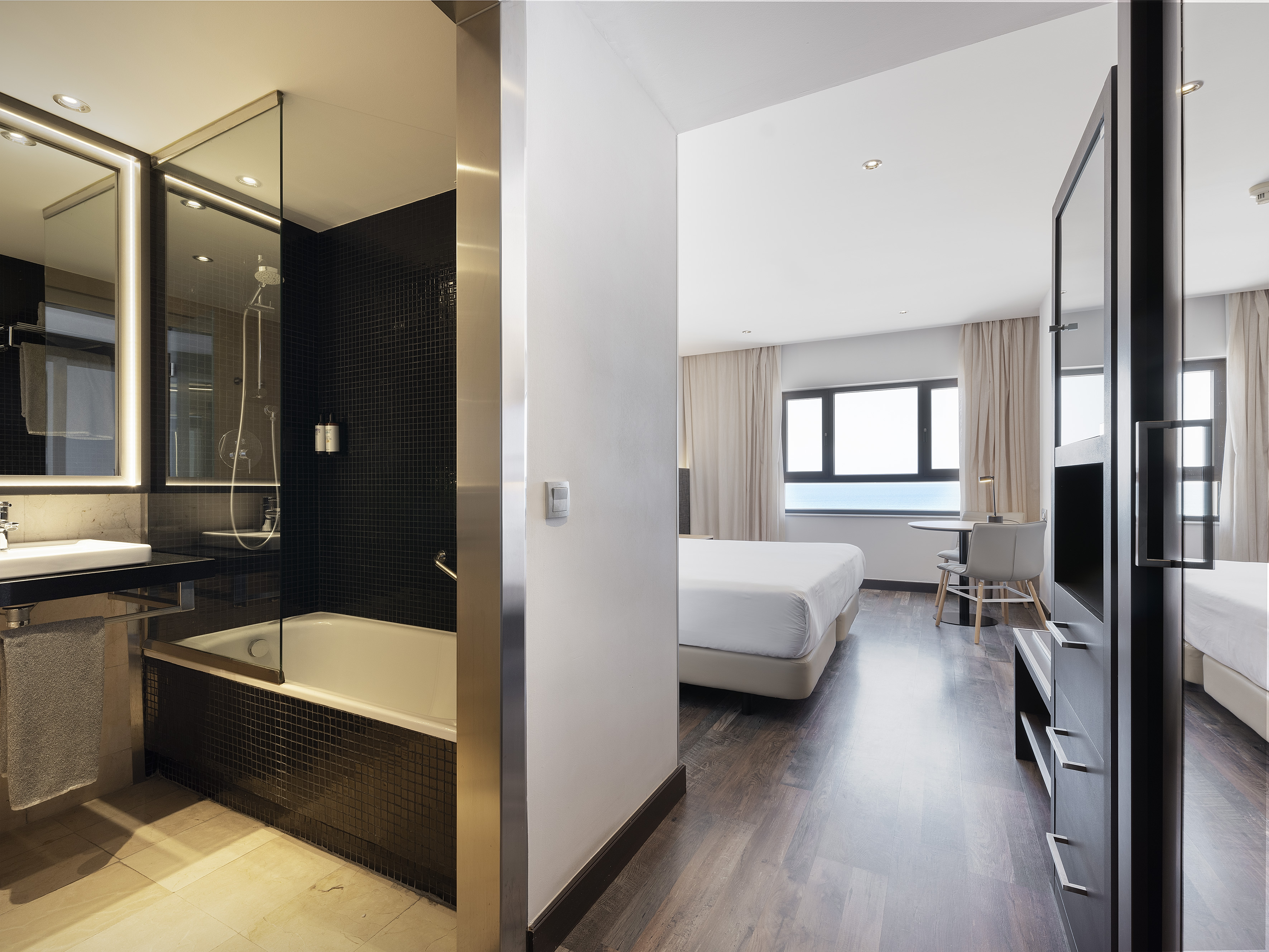 Modern hotel room with sleek bathroom and comfortable bedroom.
