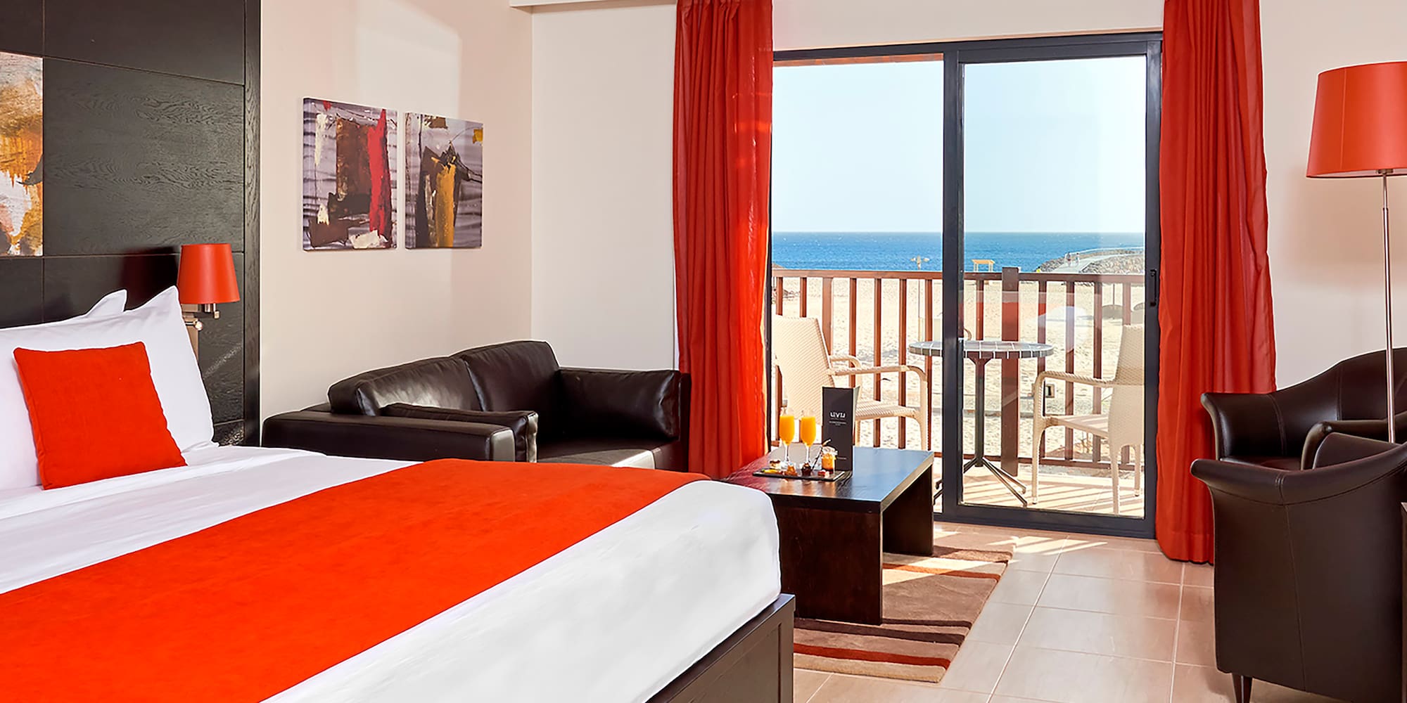 a room with a bed and a couch and a balcony overlooking the ocean