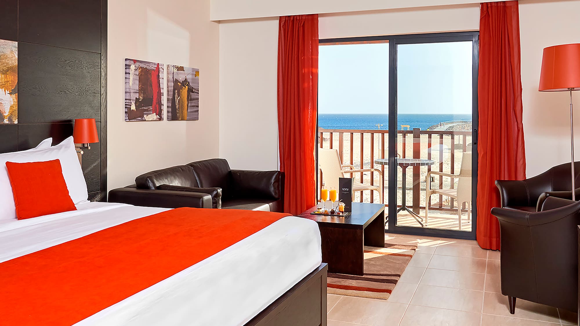 a room with a bed and a couch and a balcony overlooking the ocean