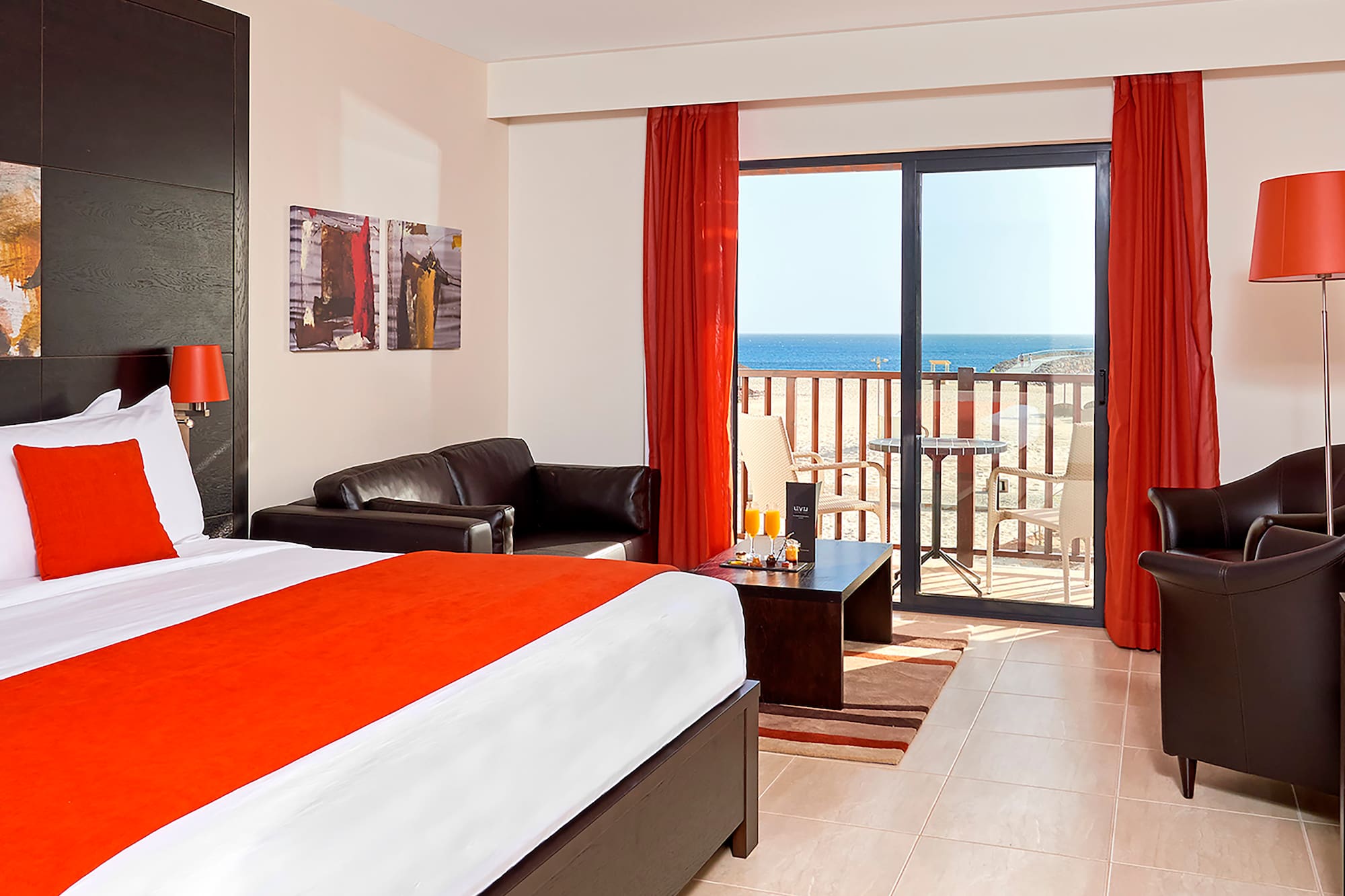 a room with a bed and a couch and a balcony overlooking the ocean