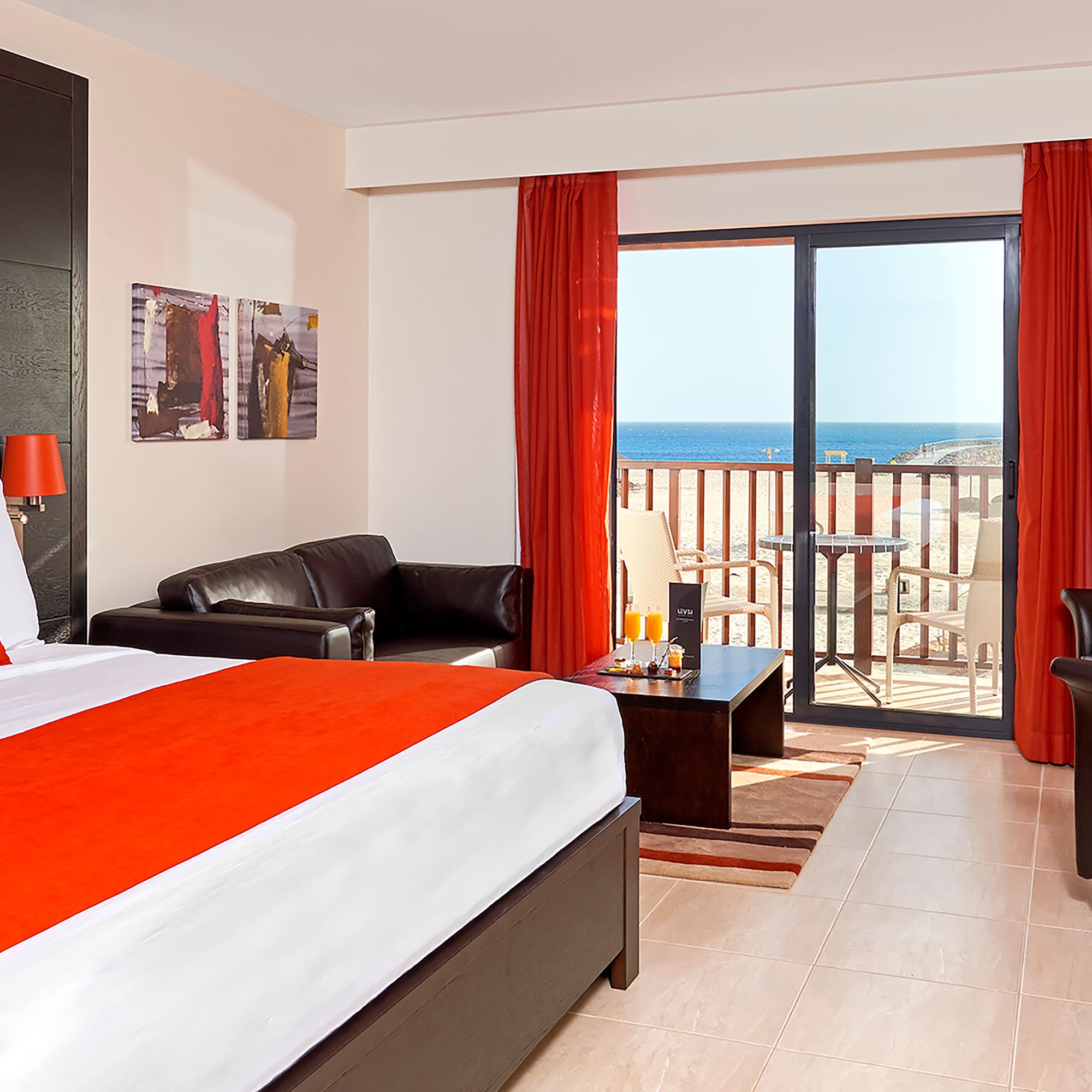 a room with a bed and a couch and a balcony overlooking the ocean