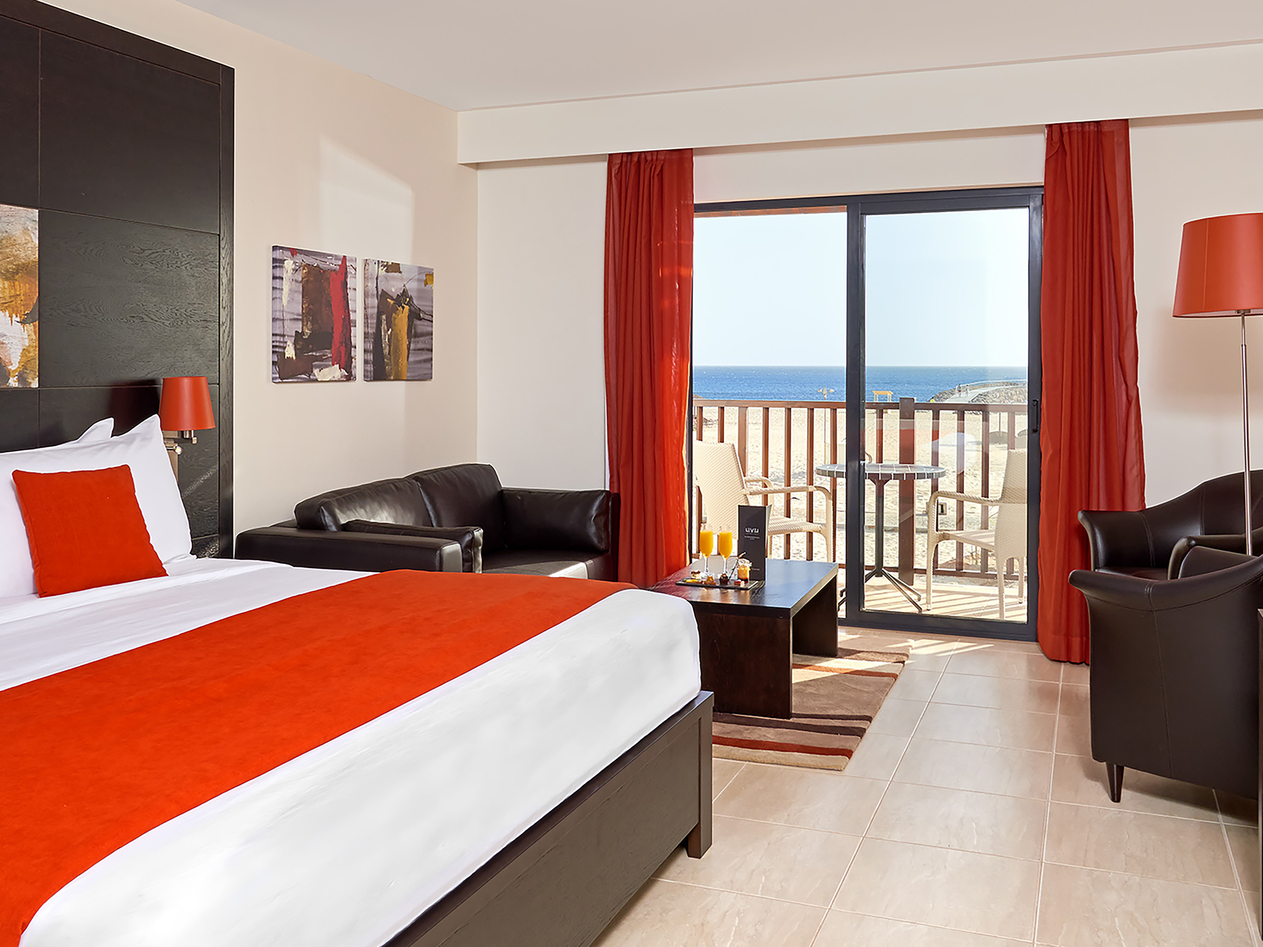 a room with a bed and a couch and a balcony overlooking the ocean