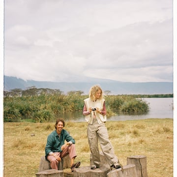 a man and woman sitting on a stump near water