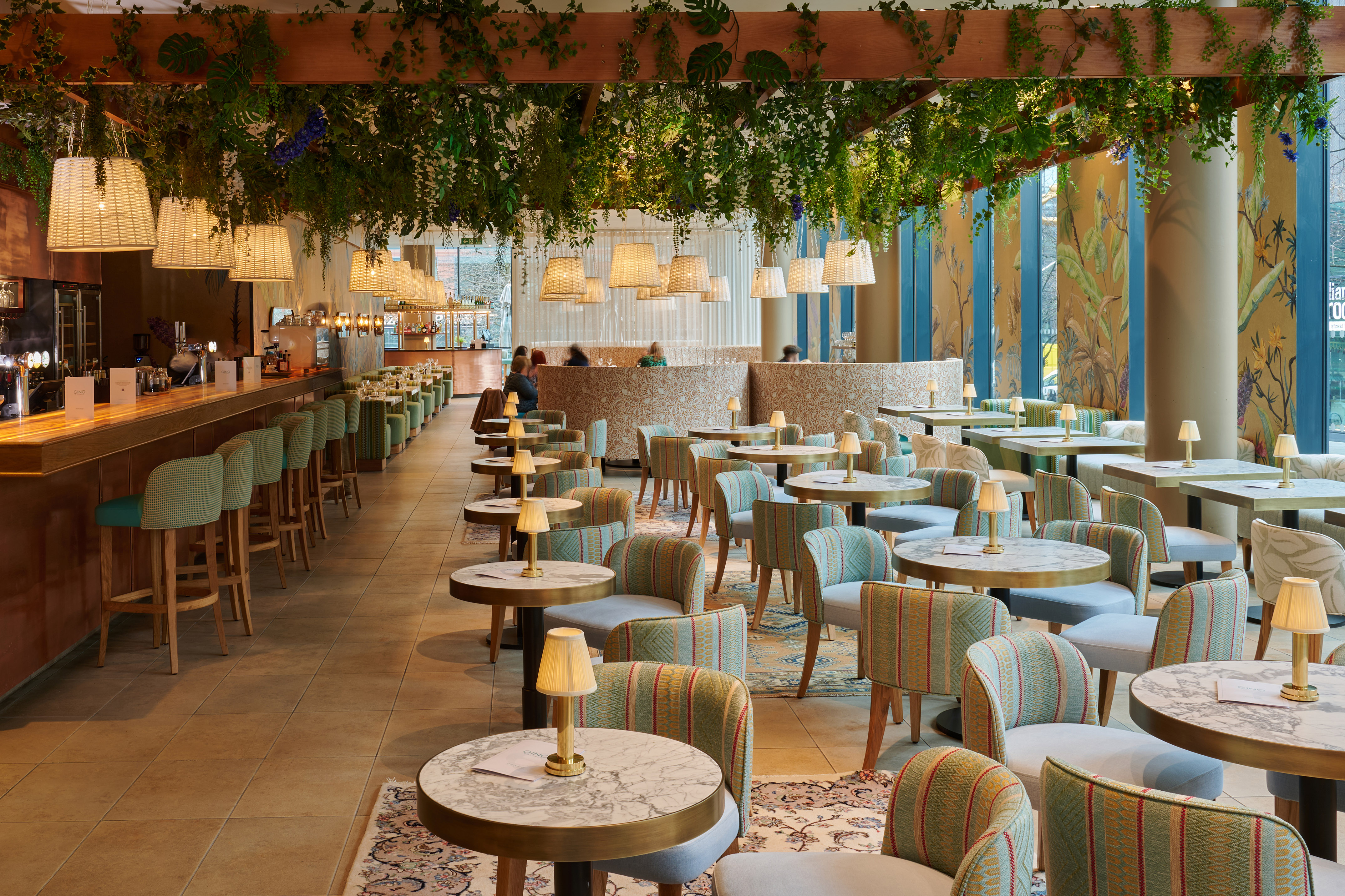 Lush restaurant bar interior with hanging plants, woven lights, and modern seating.