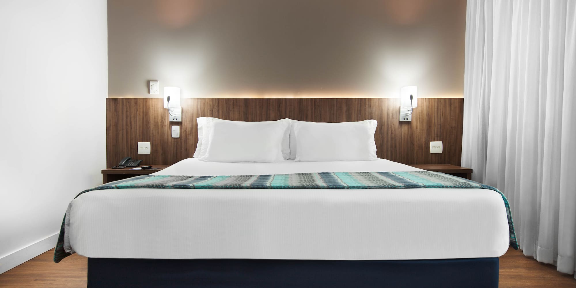 a bed with white pillows and a blue blanket