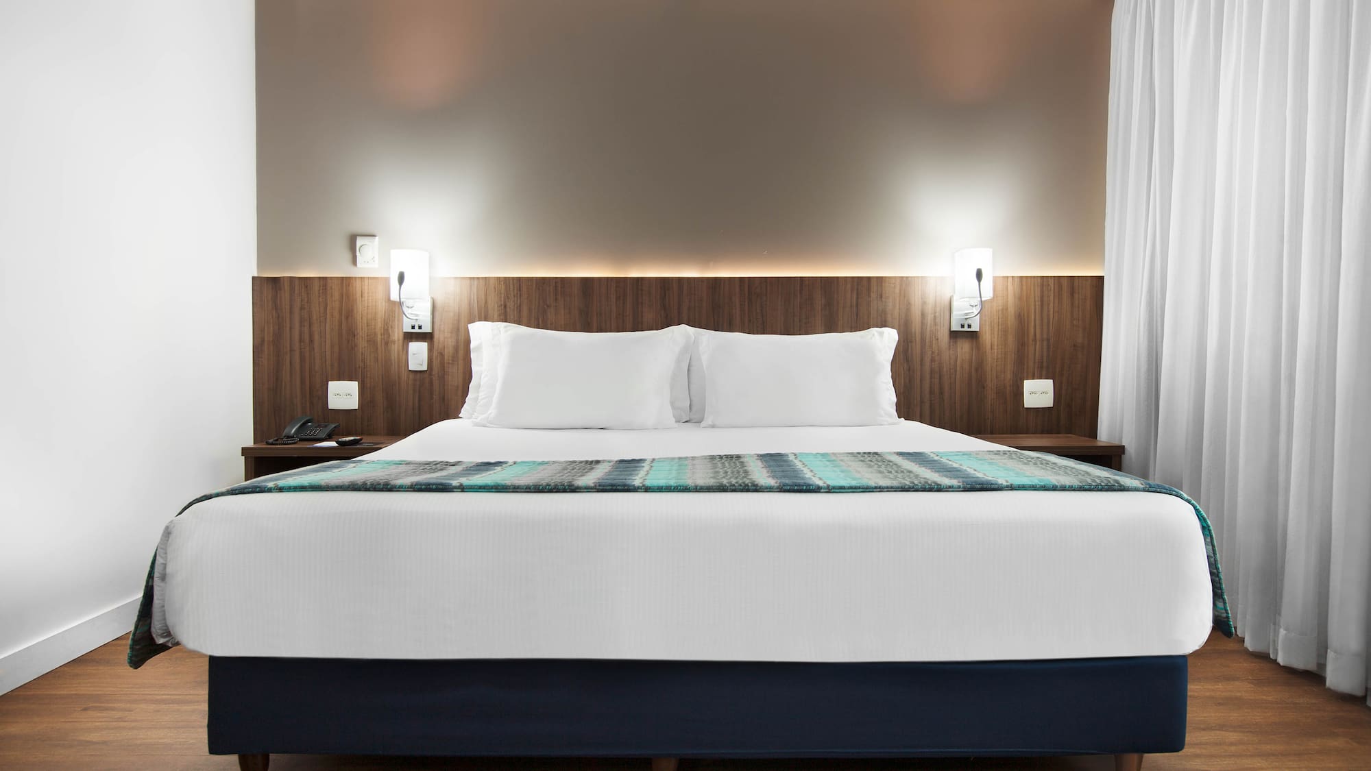 a bed with white pillows and a blue blanket