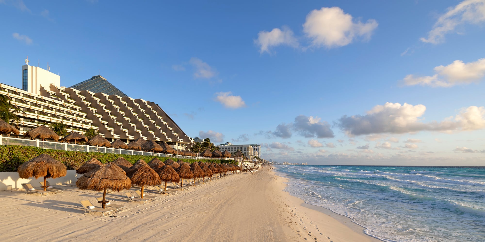 a beach with straw umbrellas and a building in the background