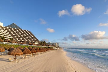 a beach with straw umbrellas and a building in the background