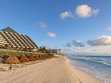 a beach with straw umbrellas and a building in the background