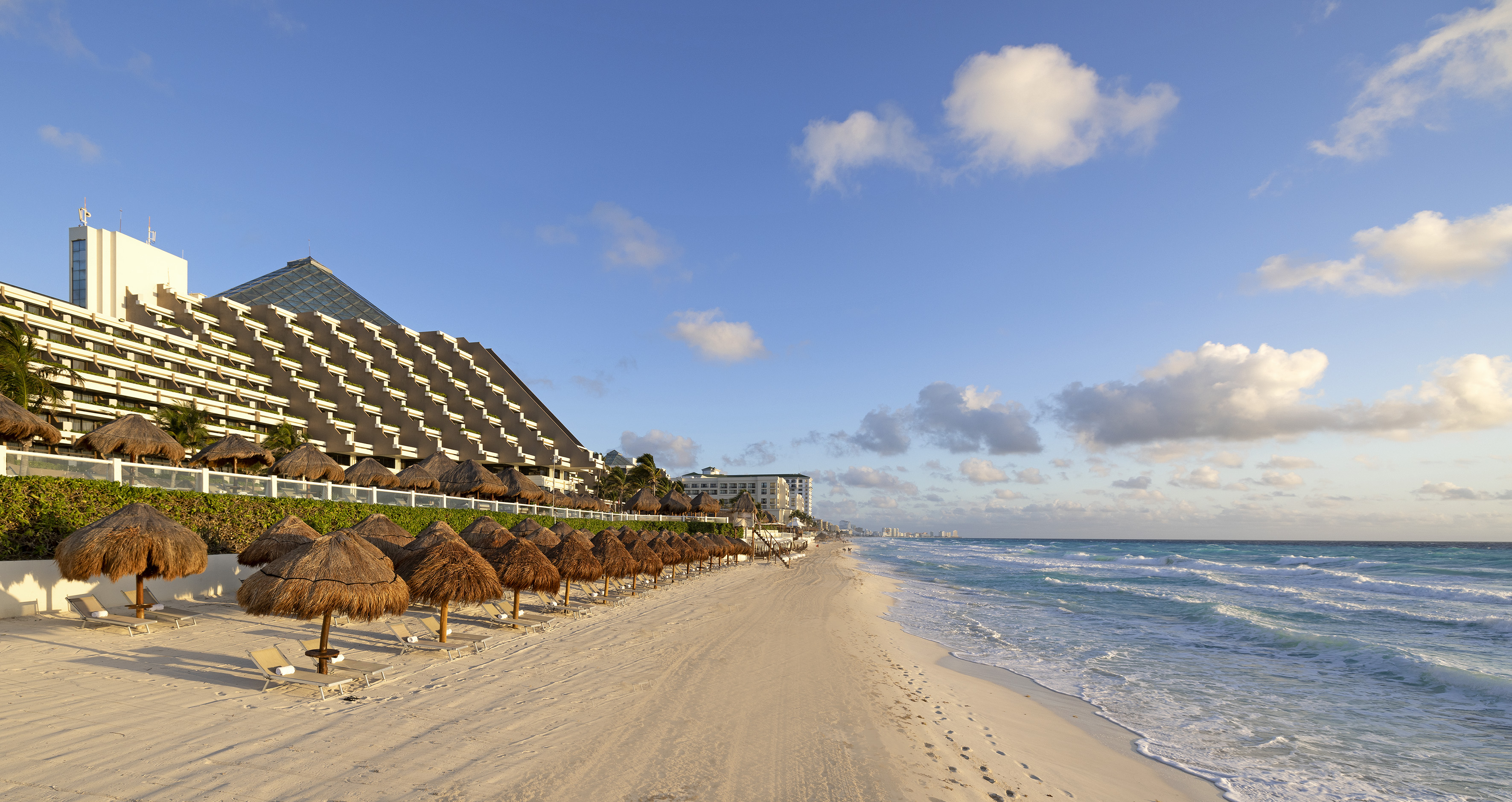a beach with straw umbrellas and a building in the background